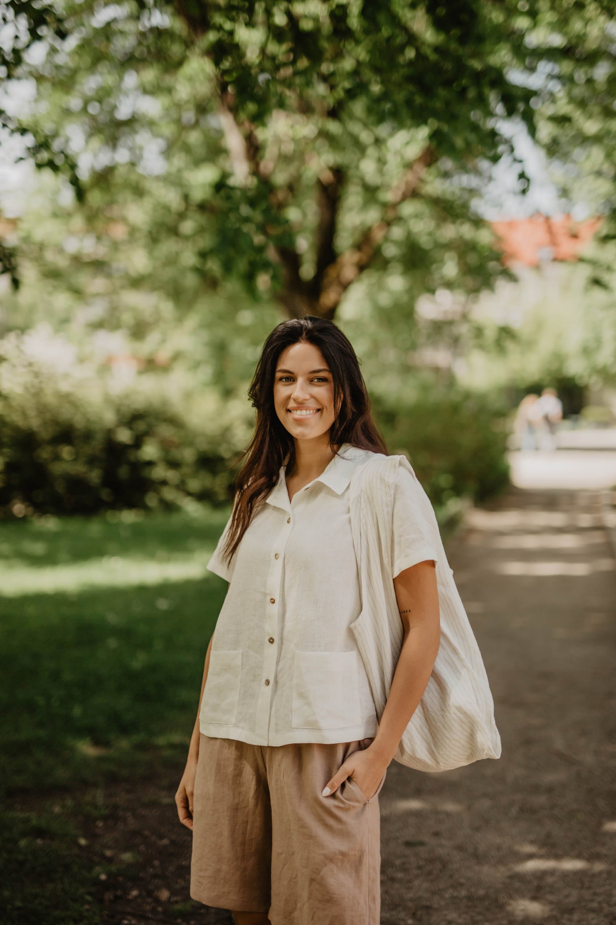 Woman With White Linen Summer Shirts And Linen Shorts Carrying A Tote Bag