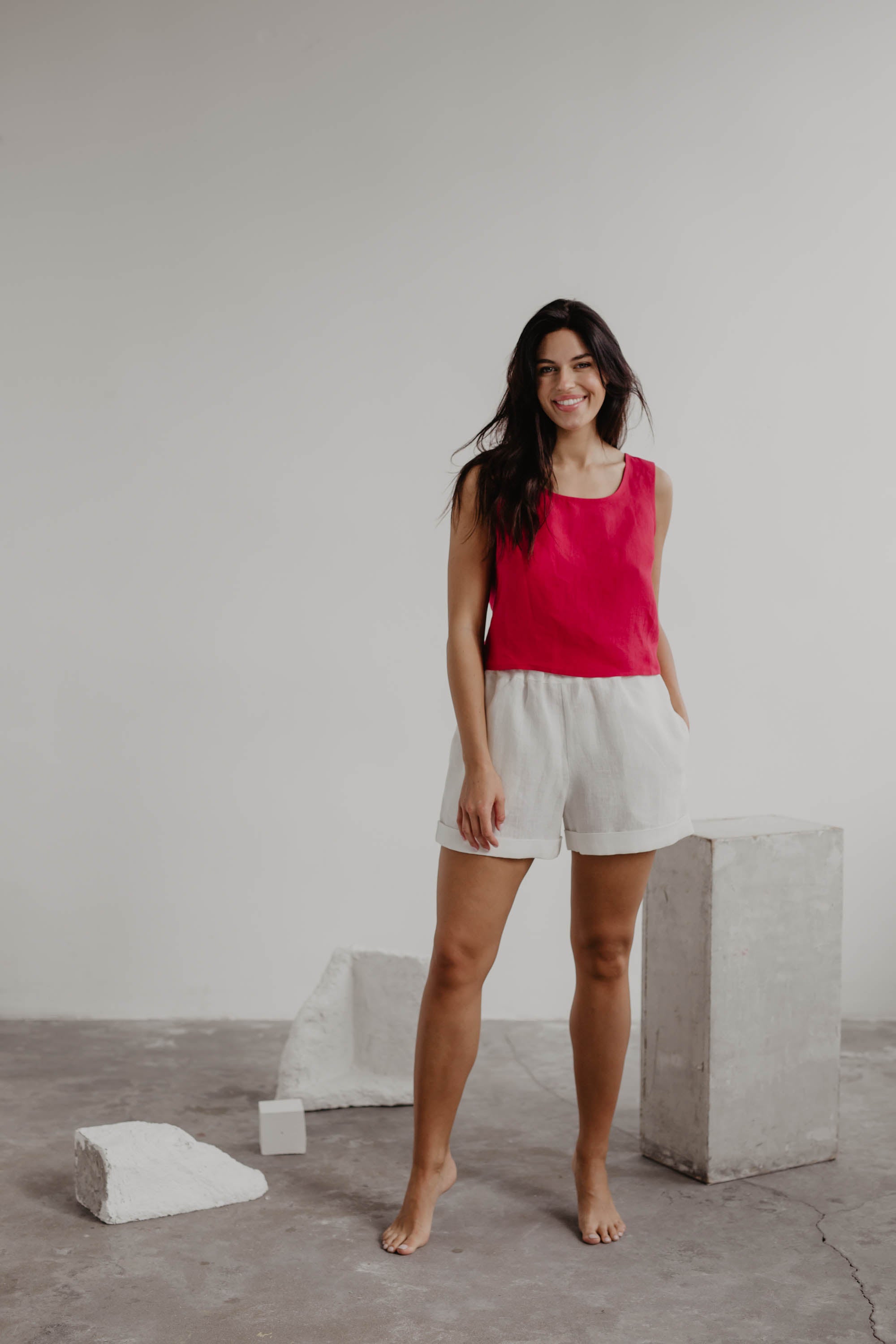 Woman In A Magenta Linen Top and White Linen Shorts Posing In A Gallery
