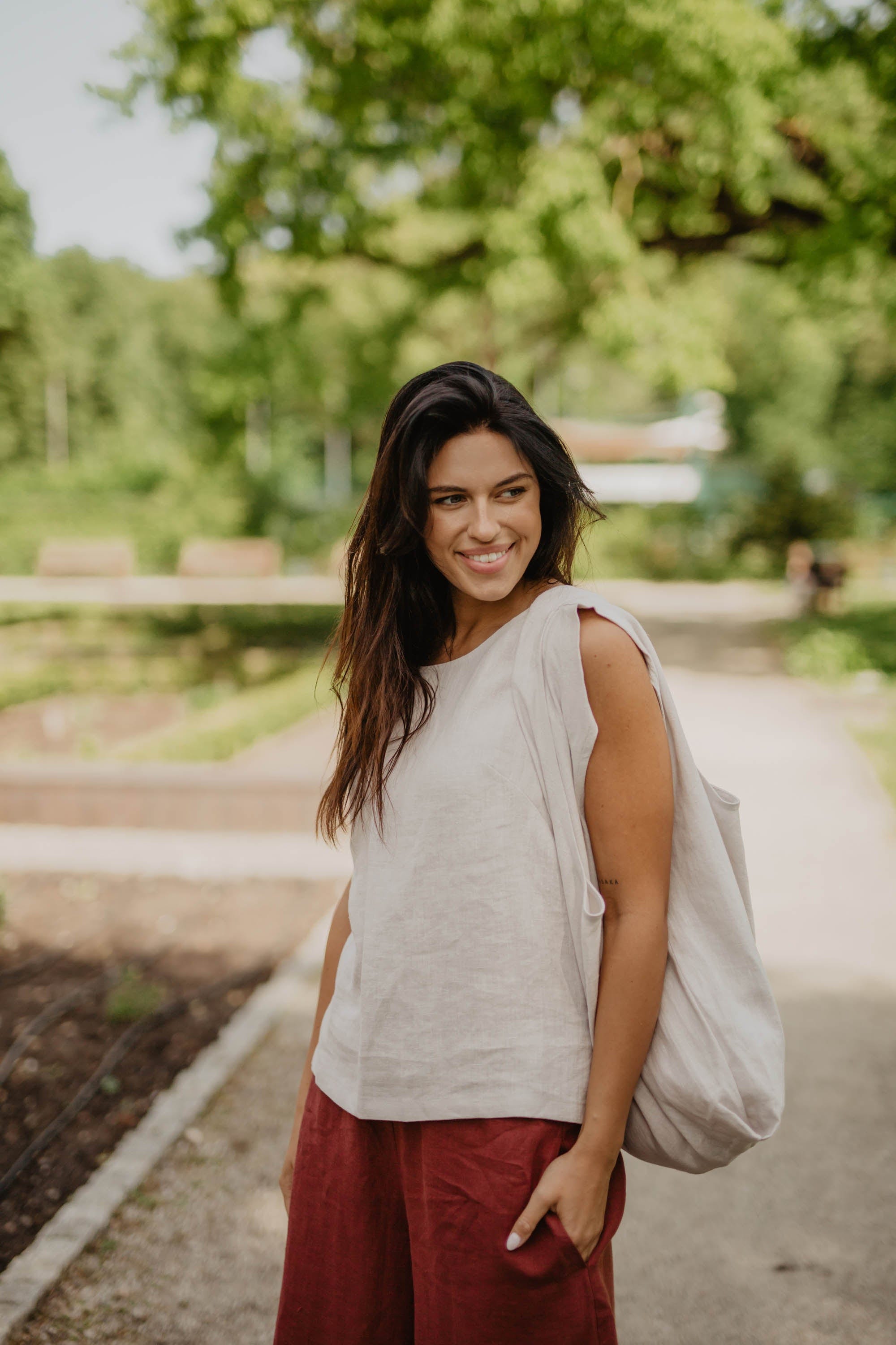 Close Up Of Woman In Park Wearing White Linen Top With Tote Bag