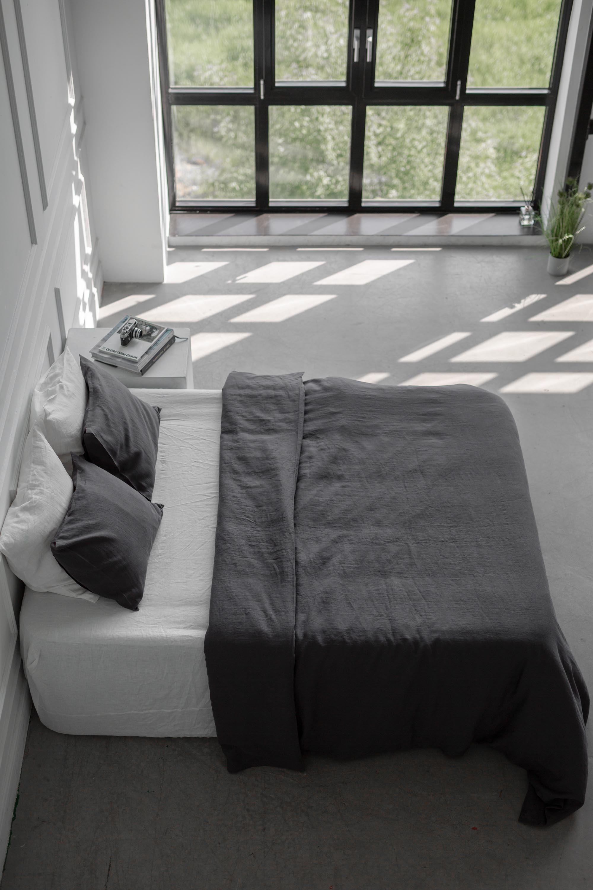 Side Top View Of Bed With Charcoal Linen Bedding Set In A White Spacious Room