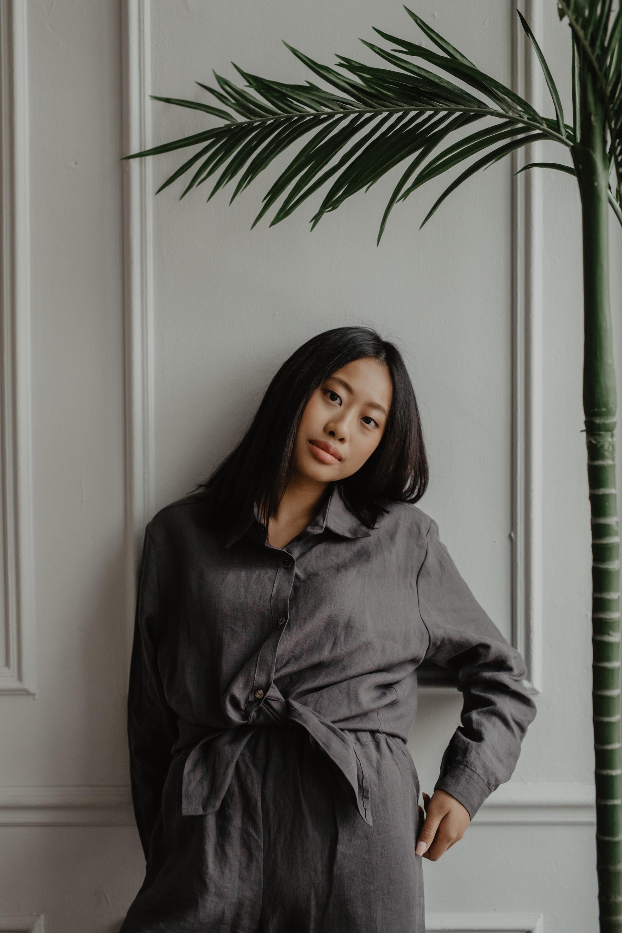 Woman Next To Plant Wearing A Charcoal Linen Casual Shirt And Charcoal Linen Pants