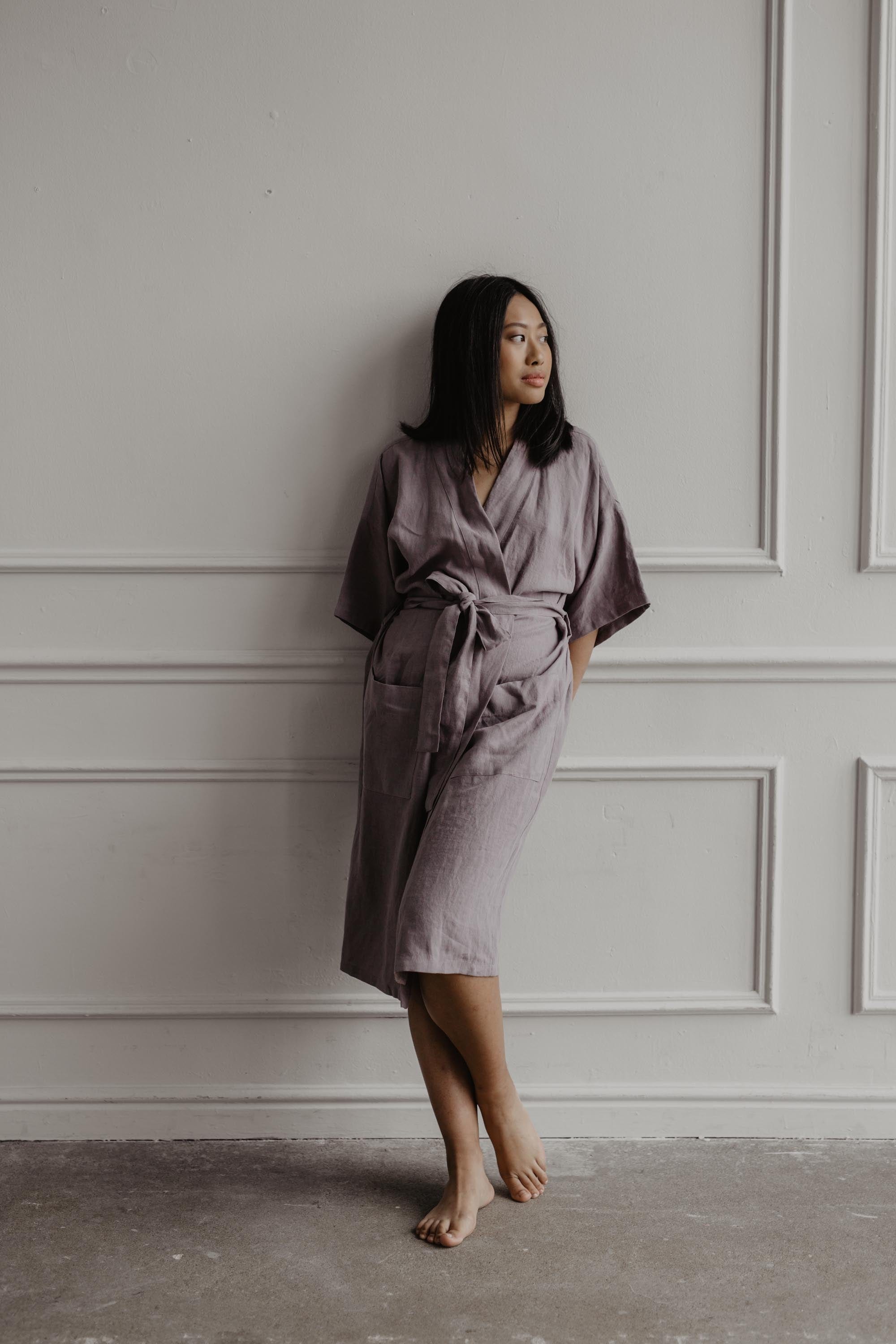 Woman Wearing A Dusty Rose Linen Bathrobe Leaning Against A Wall