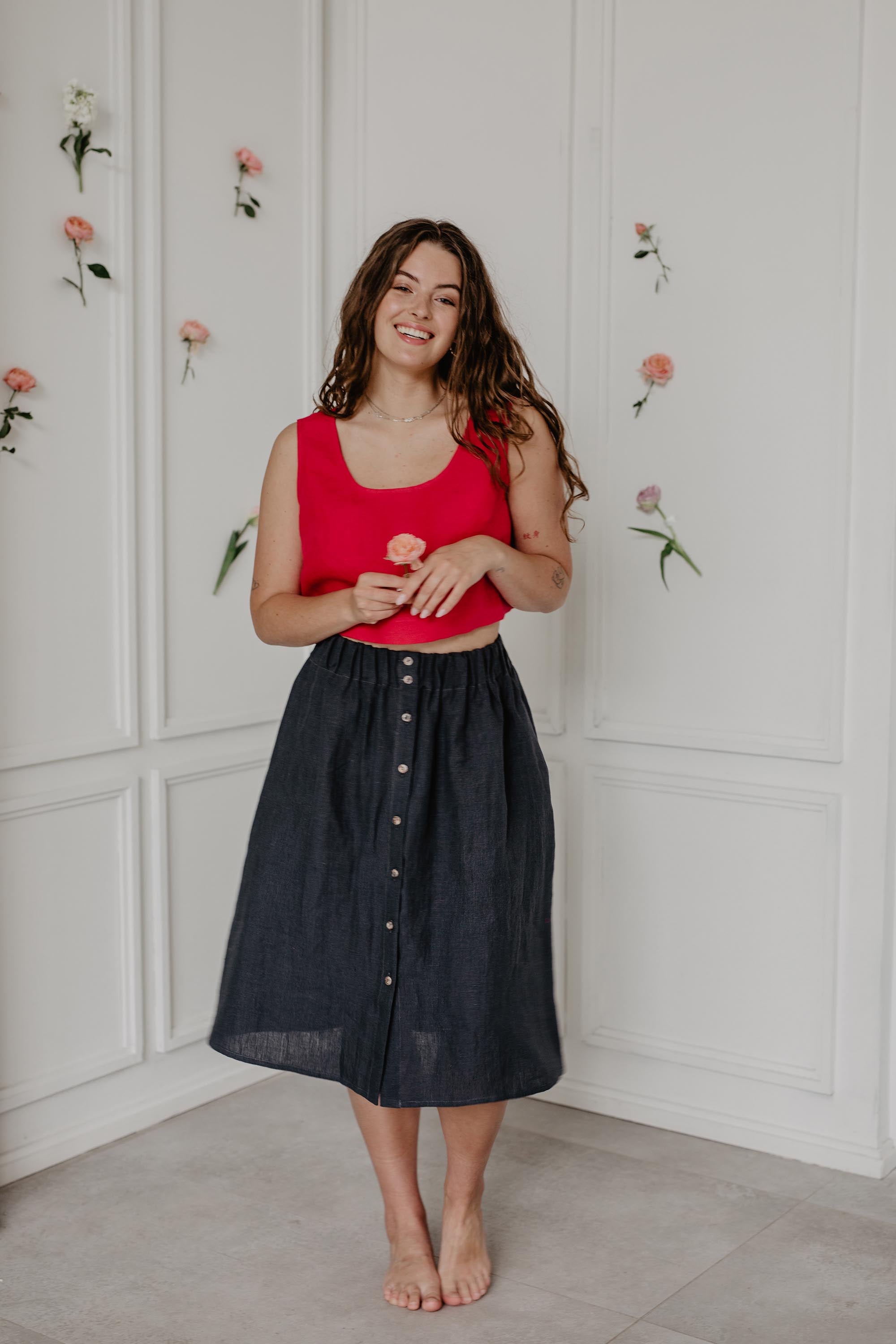 Woman Standing In Flower Room Wearing A Charcoal Linen Skirt With Buttons By AmourLinen