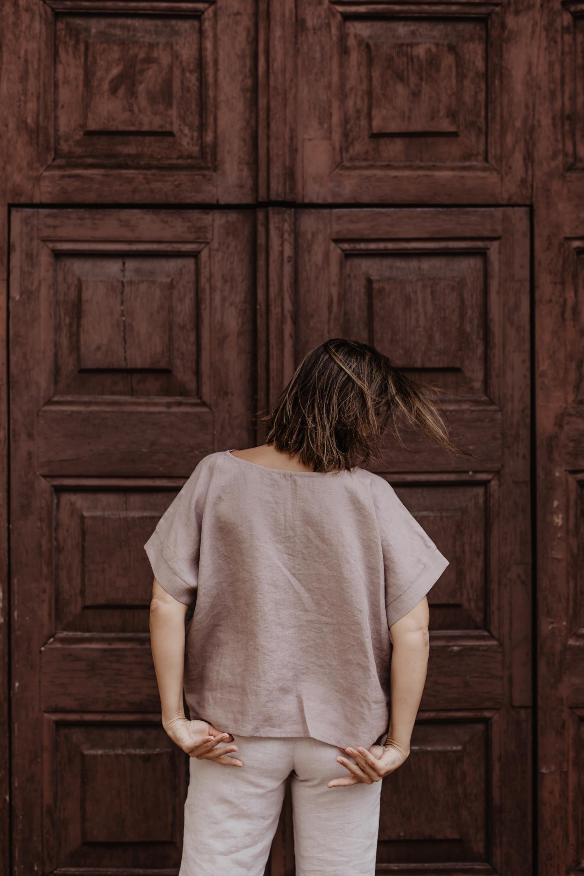 Woman Facing Back In Front Of A Door Wearing Dusty Rose Linen Top By Amourlinen