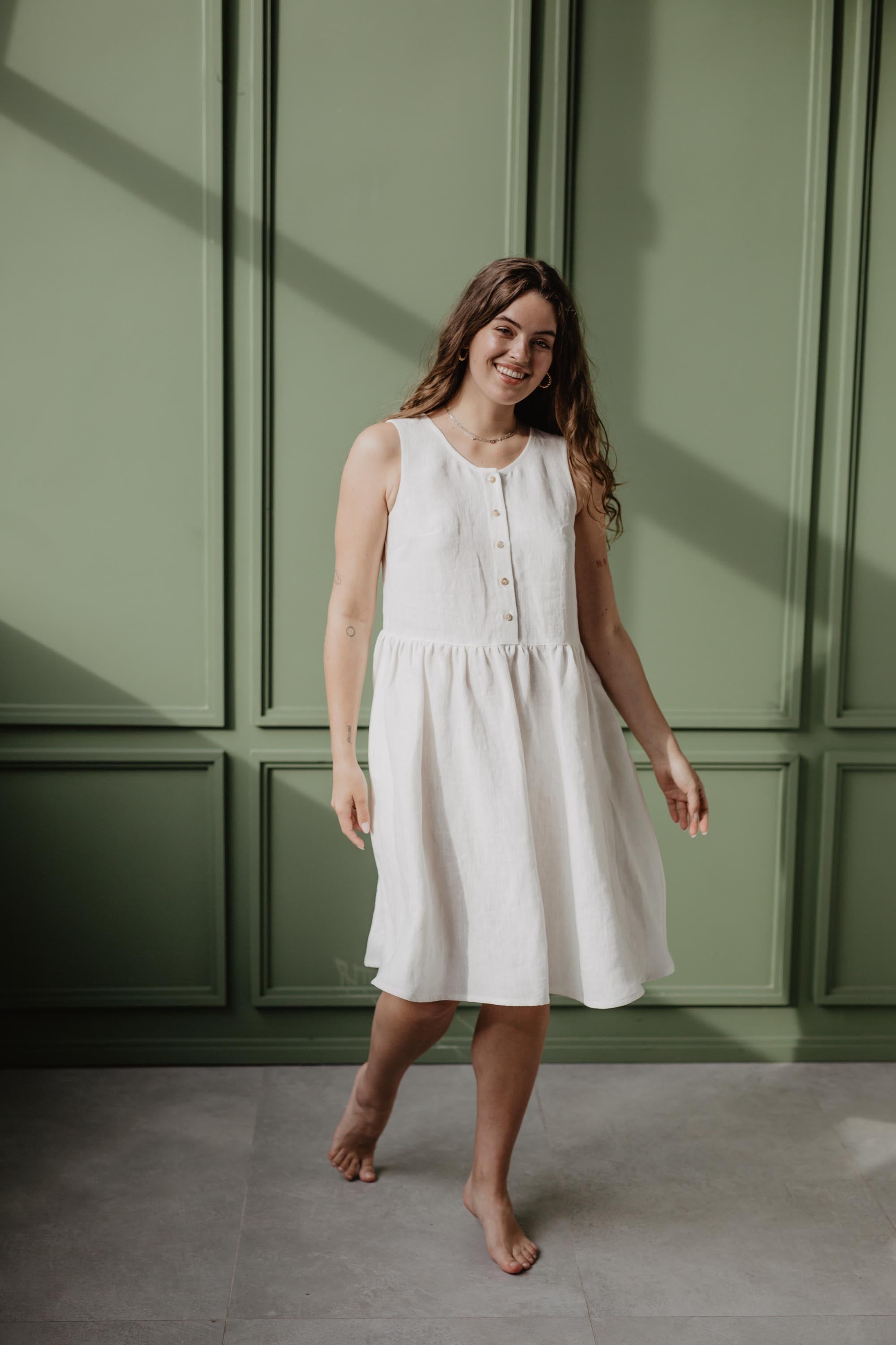 Women Stepping Wearing A white Linen Sleeveless Summer Dress by Amourlinen