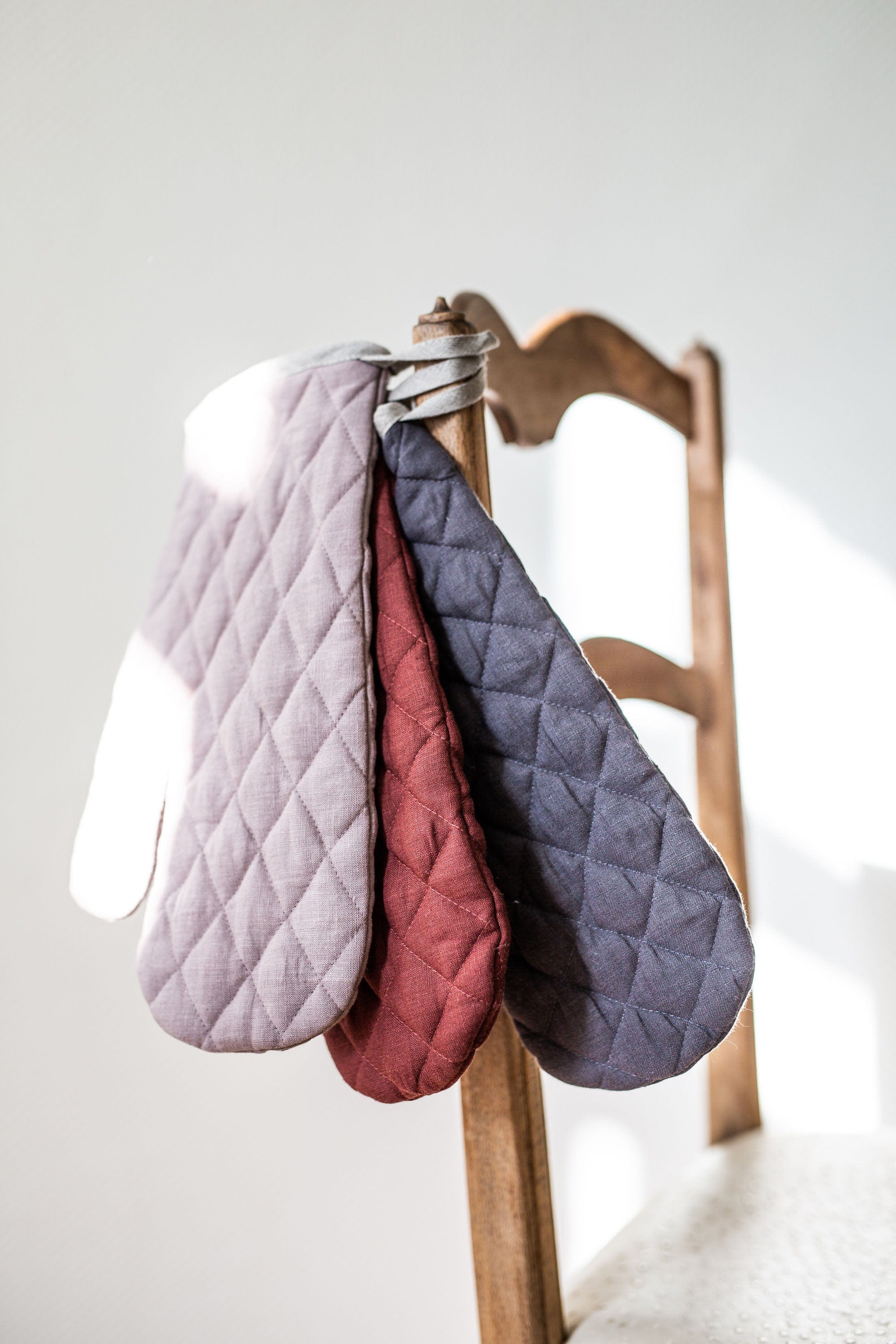 Close Up Of Various Color Linen Oven Mitts hanging on chair By Amourlinen