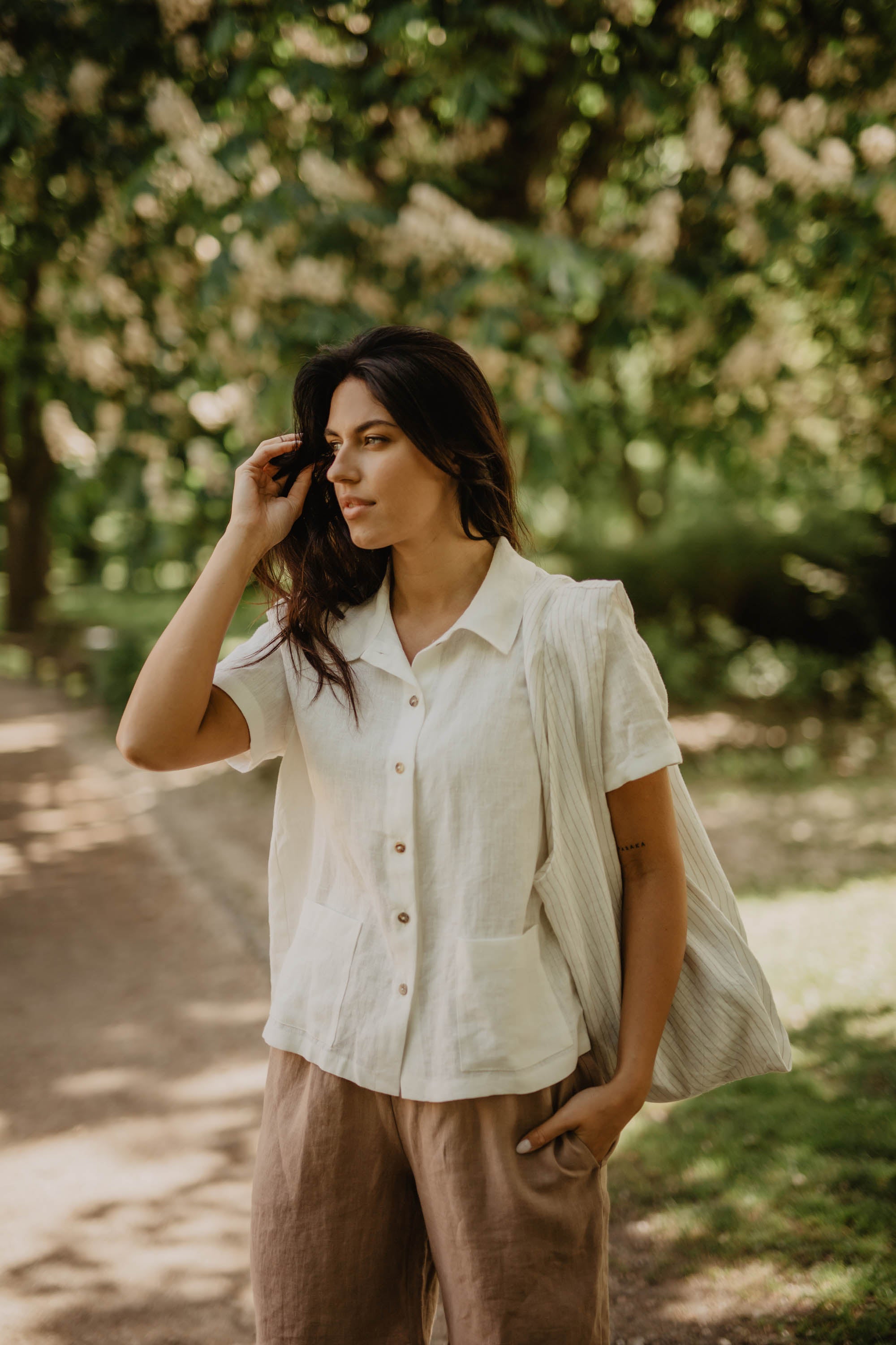 Woman Wearing A White Linen Summer Shirt And Linen Shorts in A Park