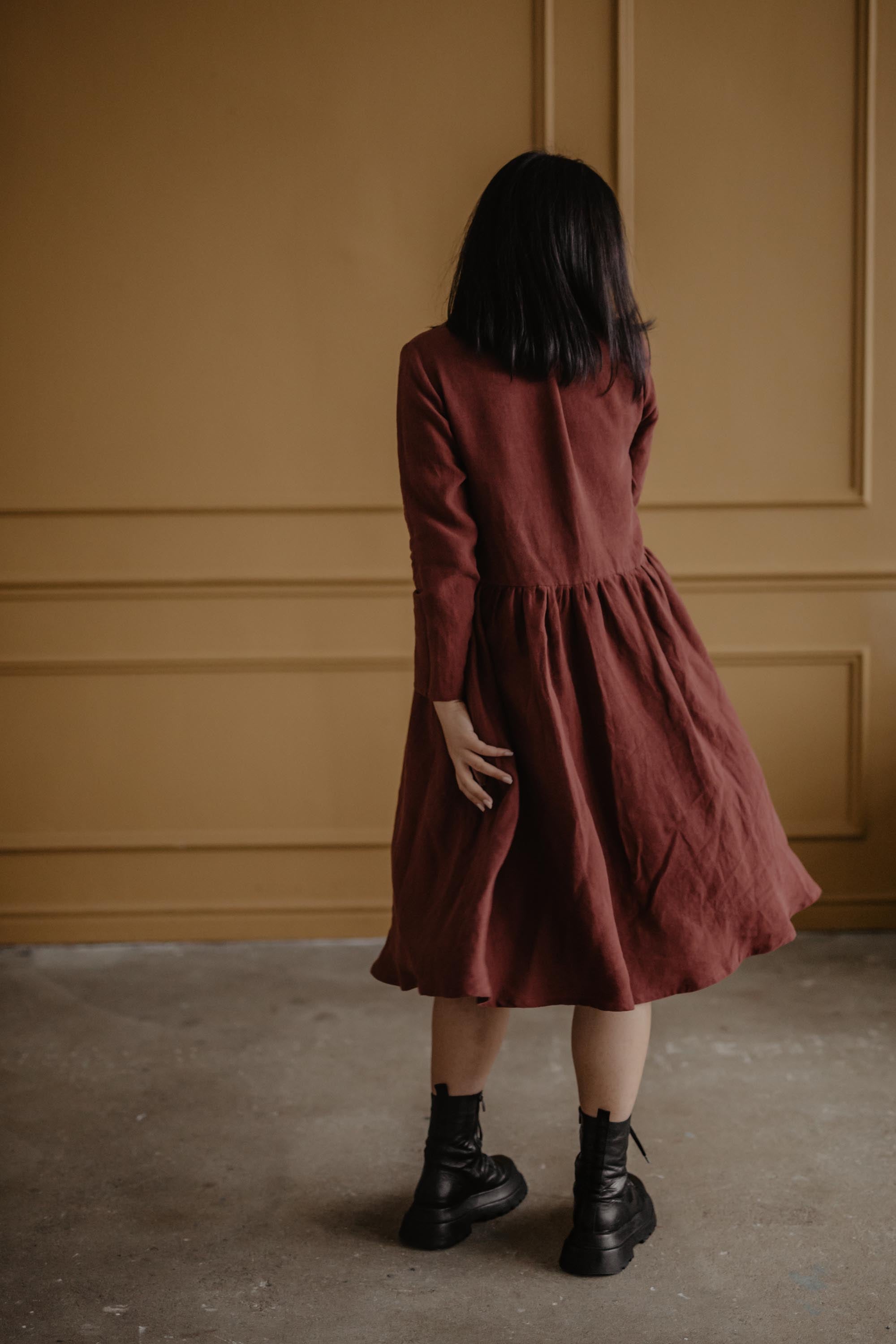 Woman Facing Back Wearing A Terracotta Mid-length Linen Dress