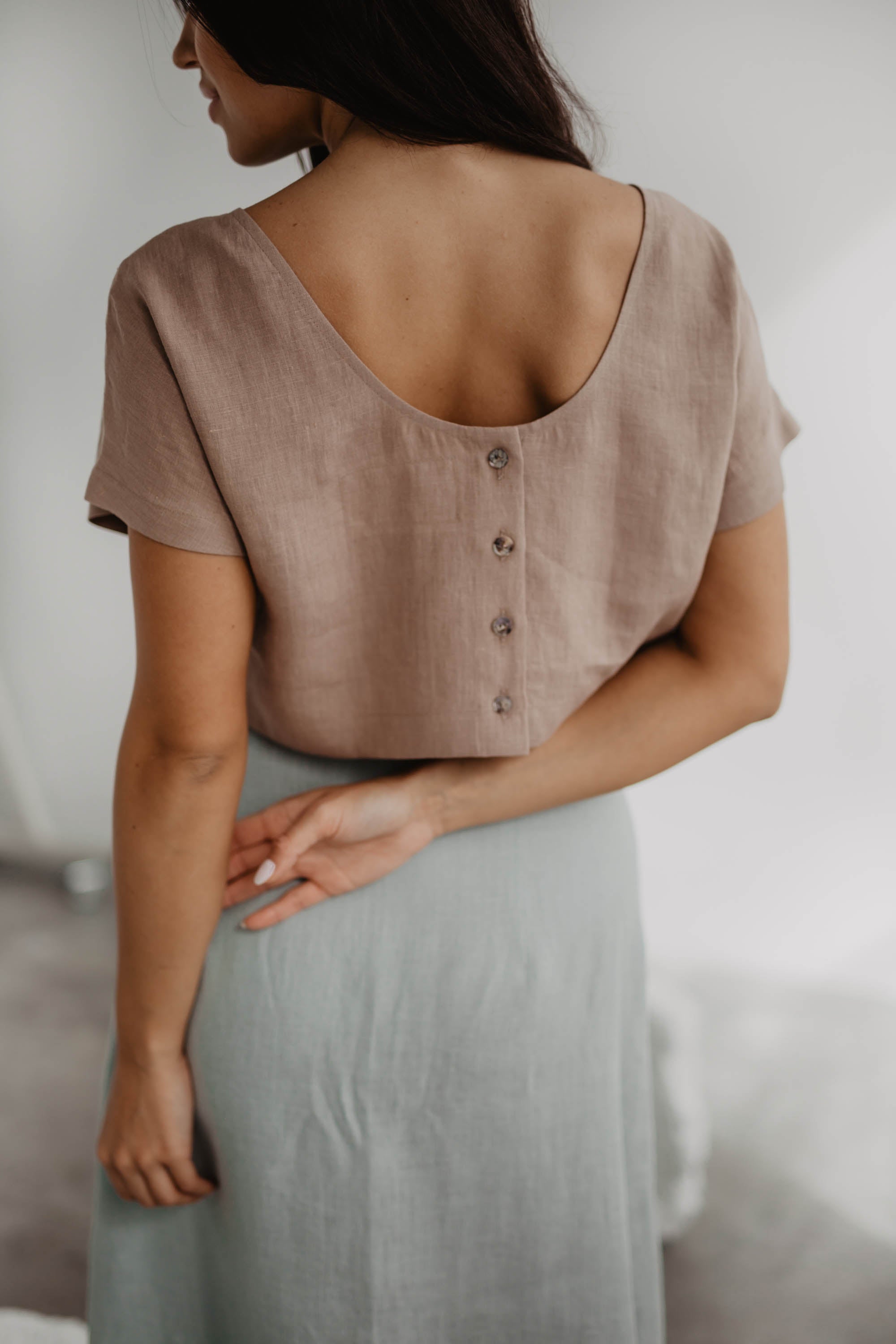 Back Of Woman Wearing A Dusty Rose Linen Crop Top With Buttons And Sage green Linen Skirt