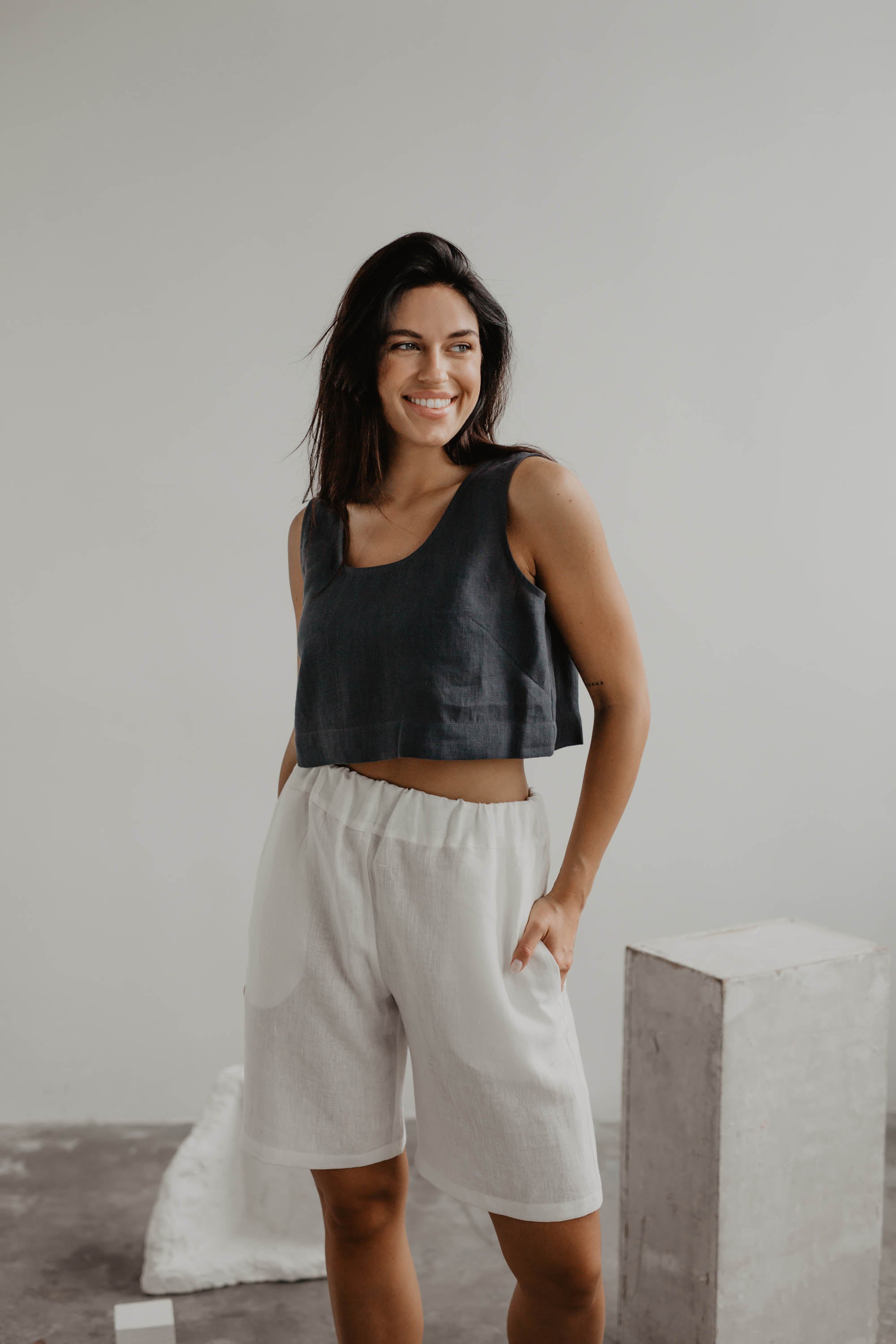 Woman Wearing Charcoal Linen Crop Top And White Linen Shorts In A Gallery