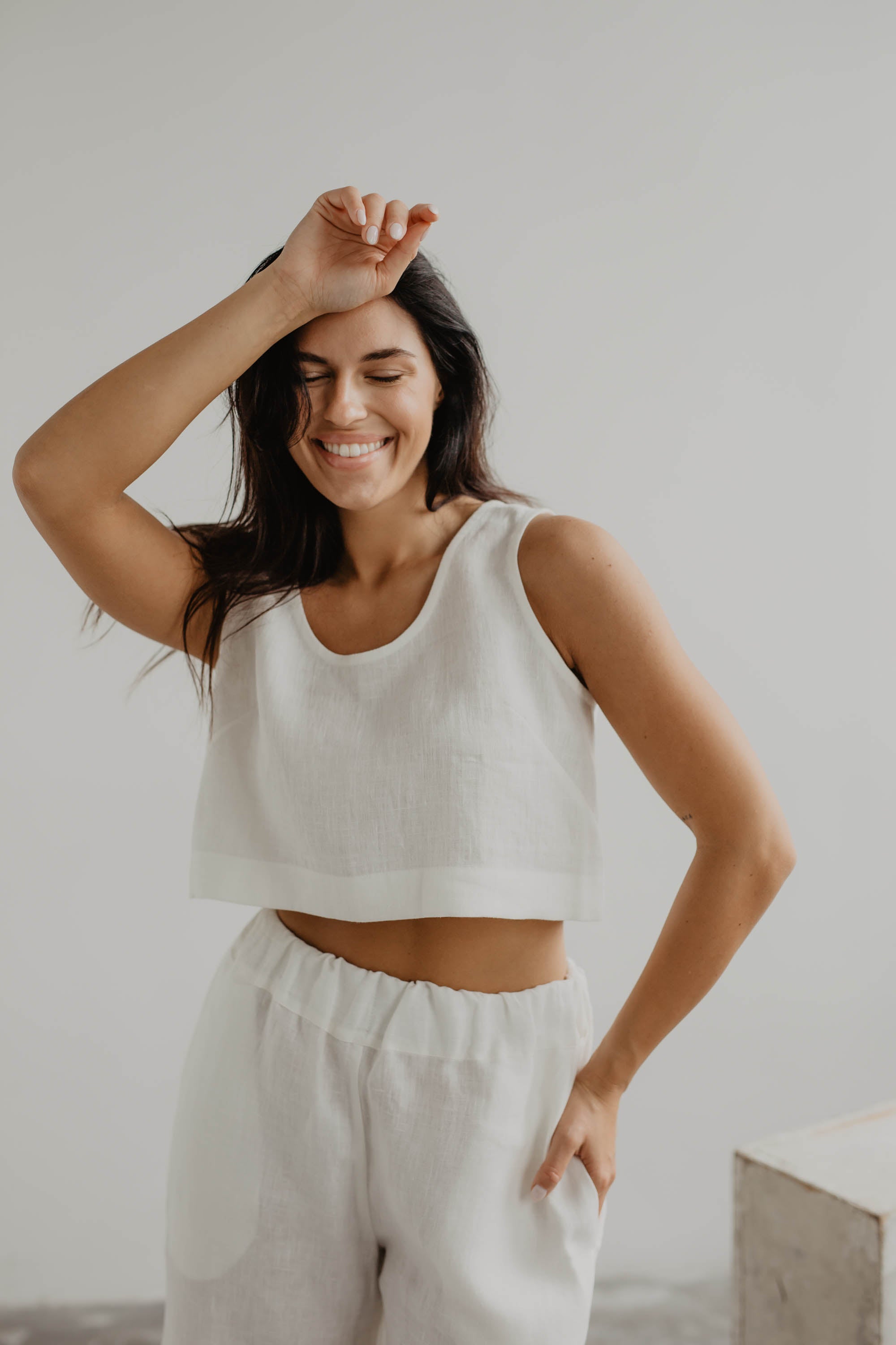 Woman Wearing A White Linen Crop Top With White Linen Shorts Posing In Gallery