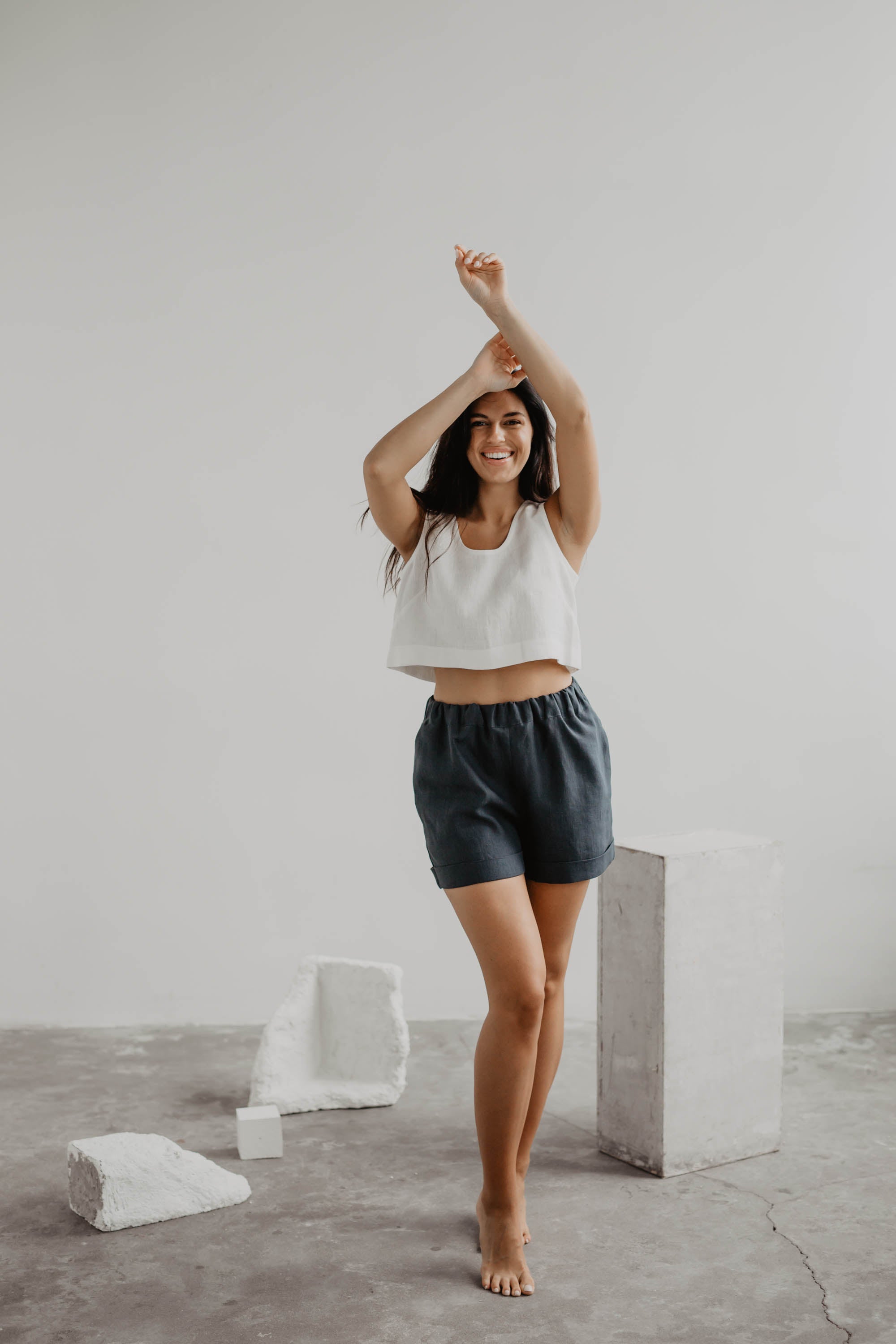 Woman Posing In A Gallery Wearing Charcoal Linen Shorts and A White Linen Top