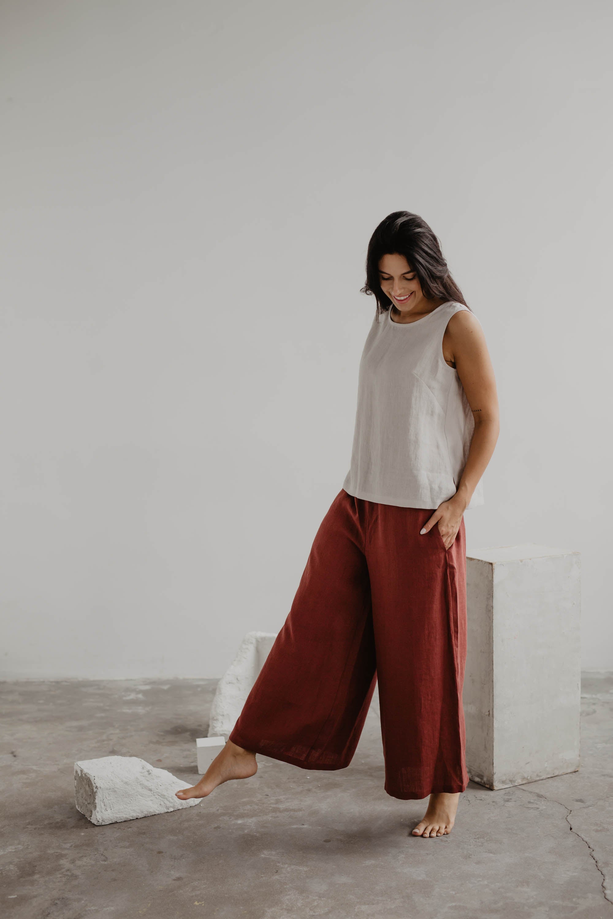 Woman Wearing Terracotta Wide Linen Pants and White Linen Top In A Gallery
