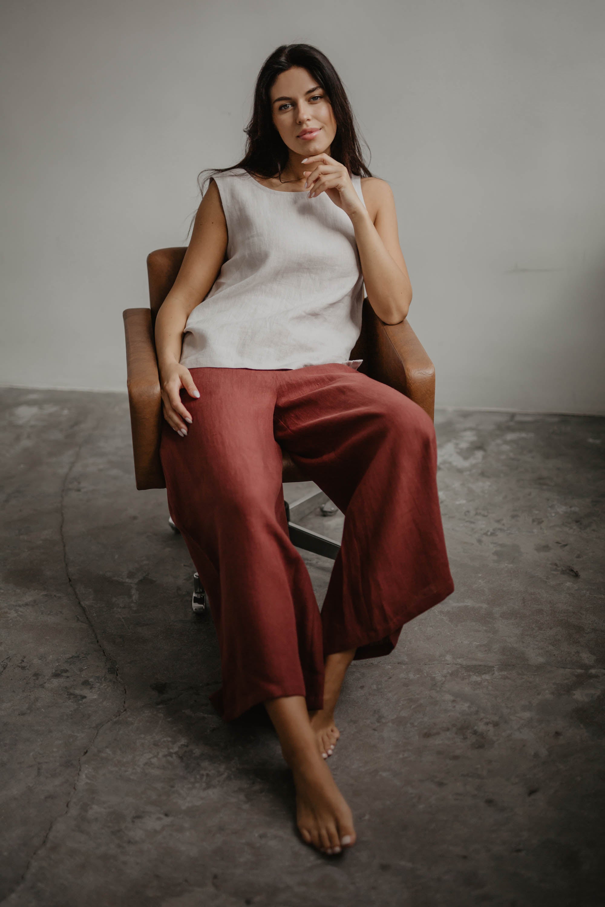 Woman Sitting In A Chair Wearing Wide Red Linen Pants and White Top