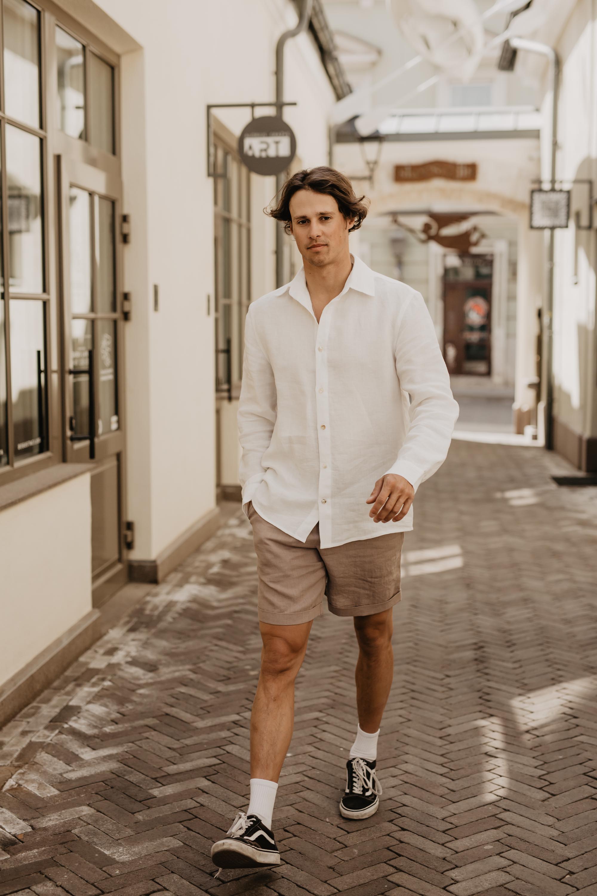 Man Walking Up the Street Wearing Dusty Rose Linen Shorts And White Shirt