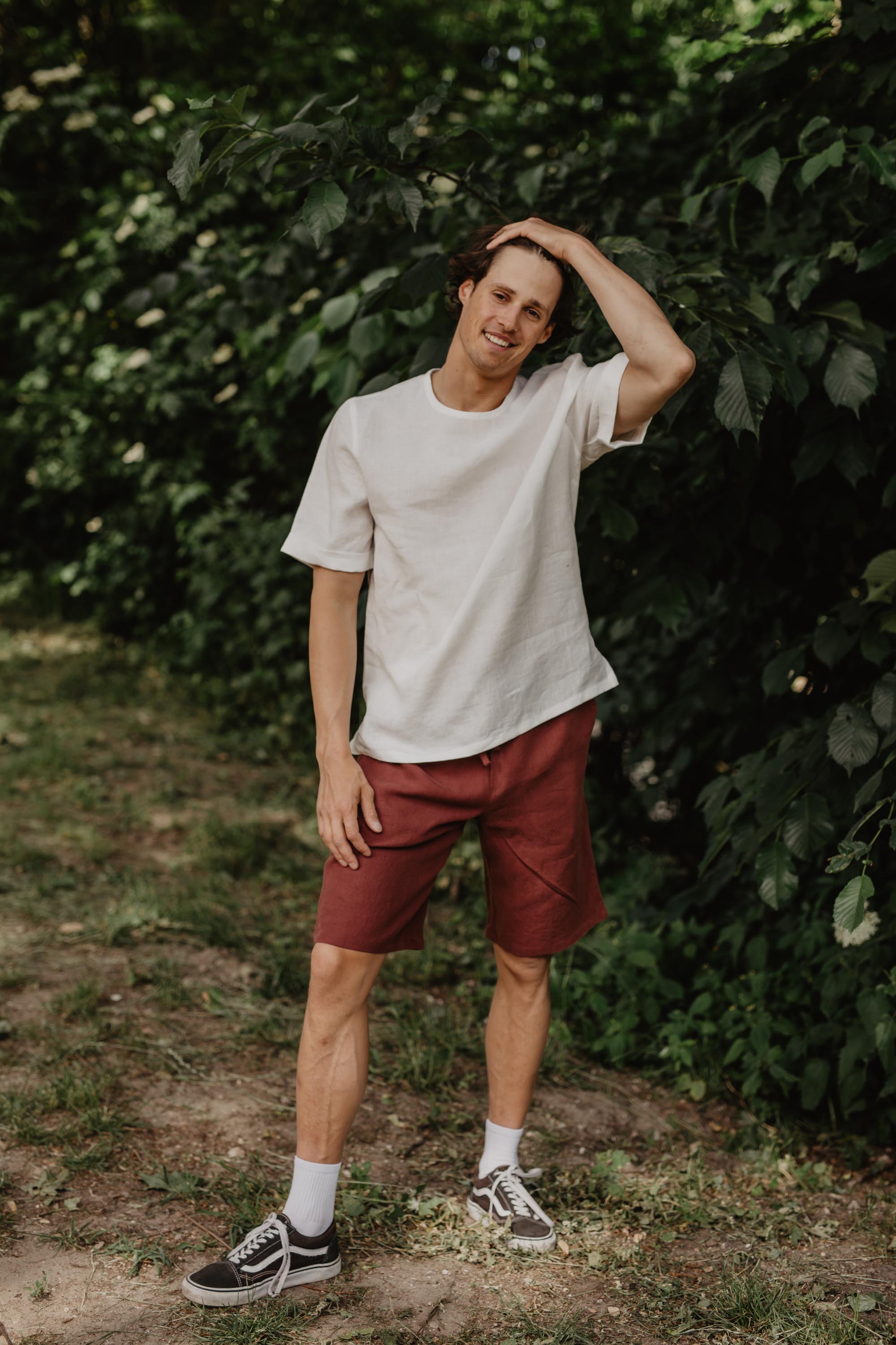 Front Facing Man Wearing A White LInen Top and Terracotta Linen Shorts