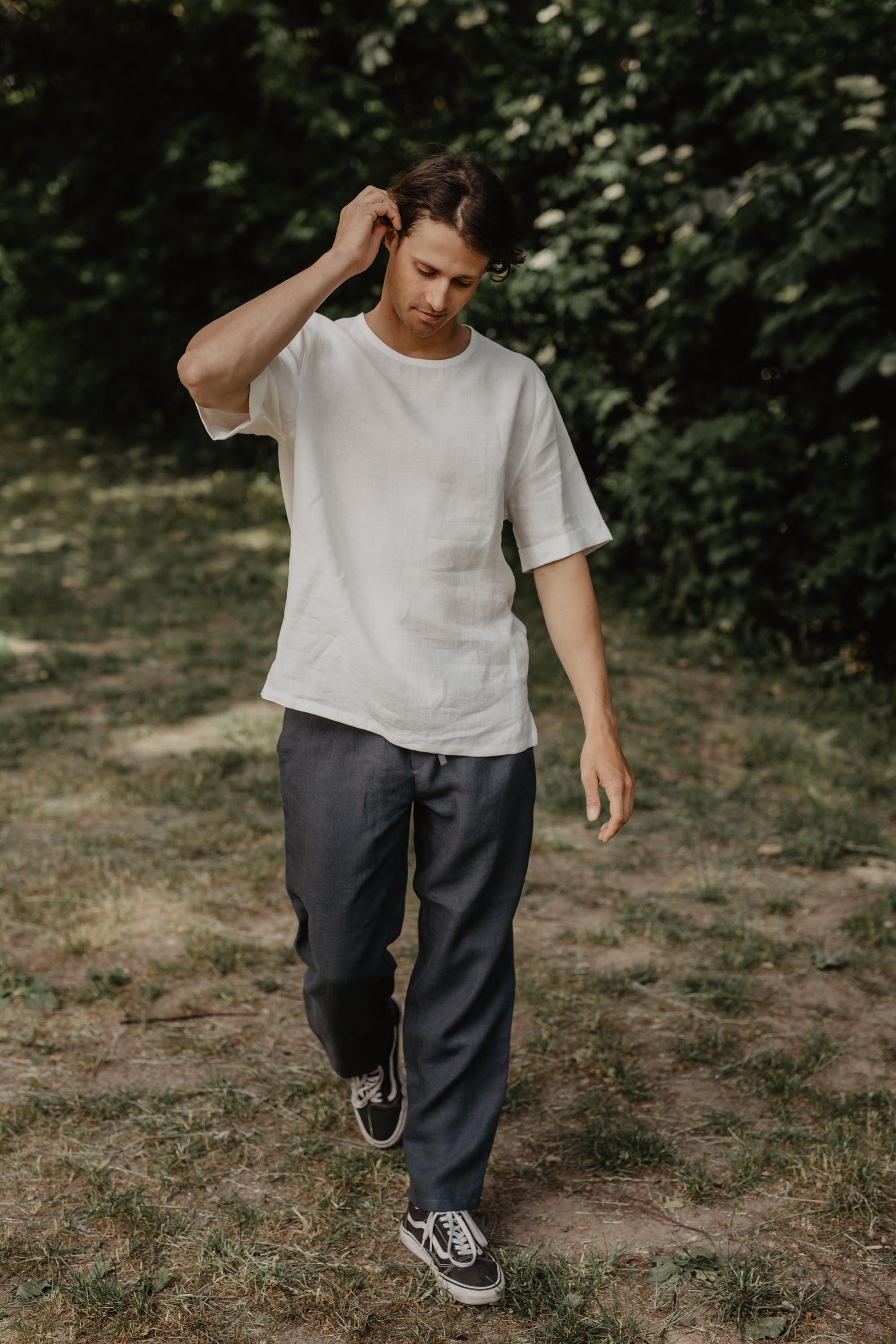 Man Walking In Nature Wearing A White Linen T-Shirt and Black Linen Pants