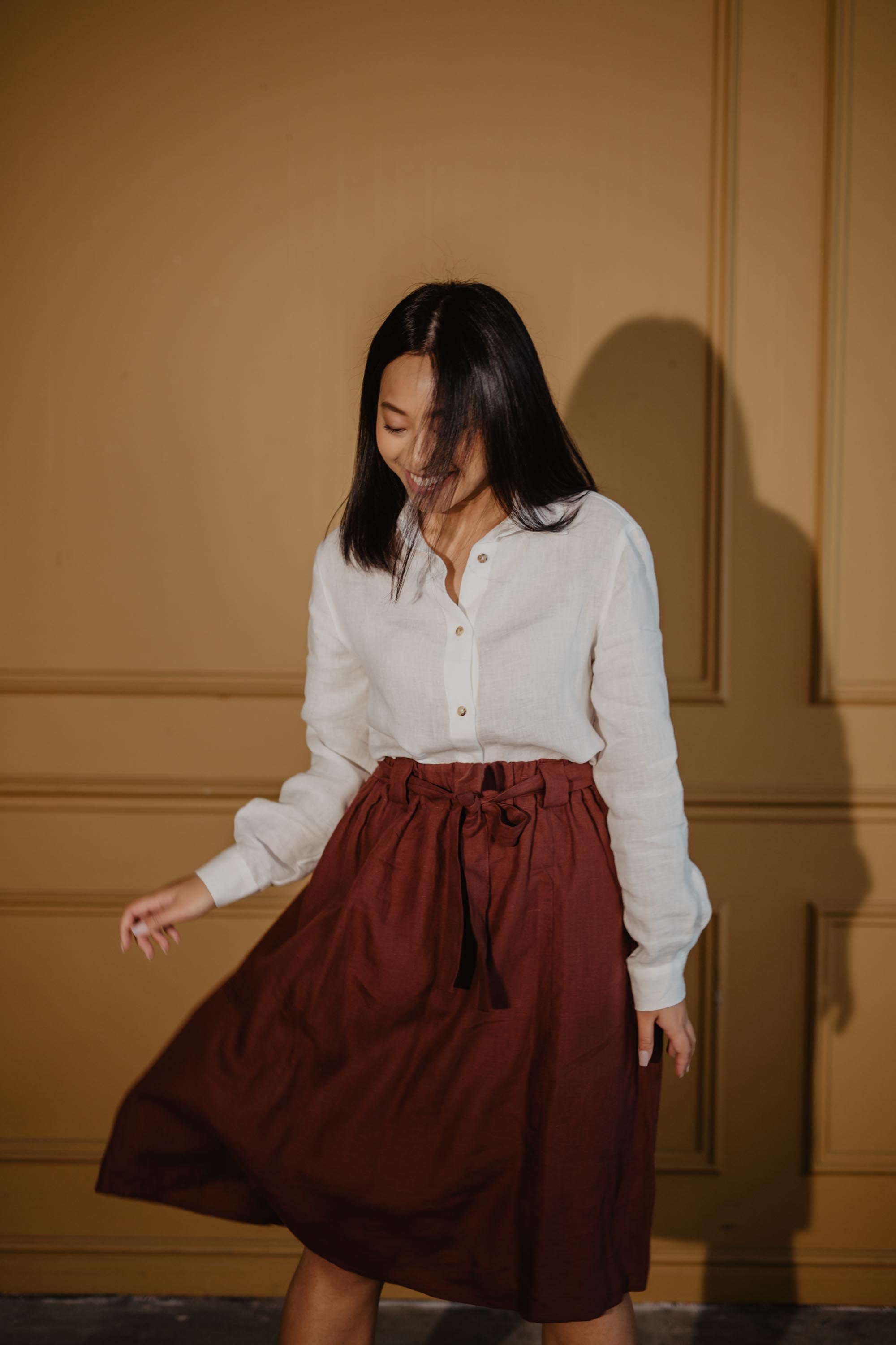 Woman Dancing In Terracotta Bergen Mid-length Linen Skirt and White Linen Shirt