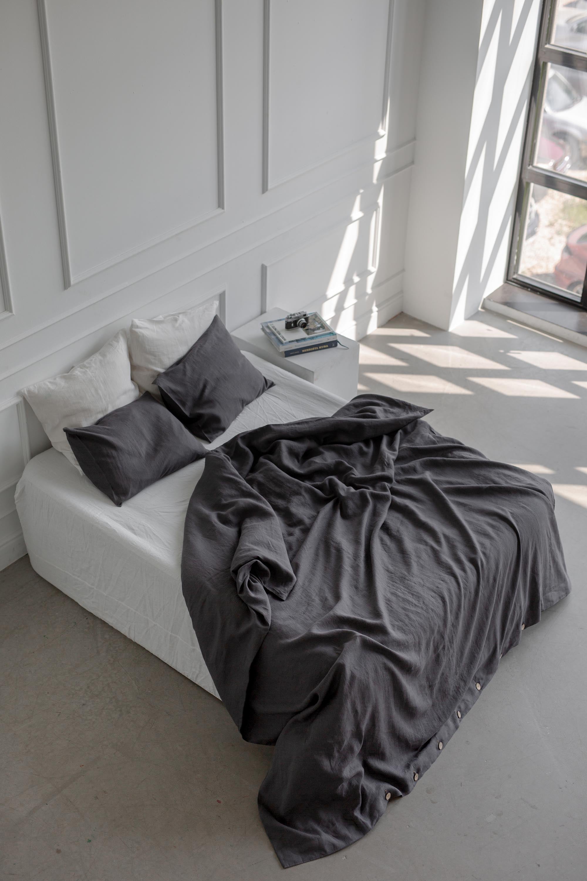 Top View Of Bed With Charcoal Linen Bedding Set In A White Spacious Room
