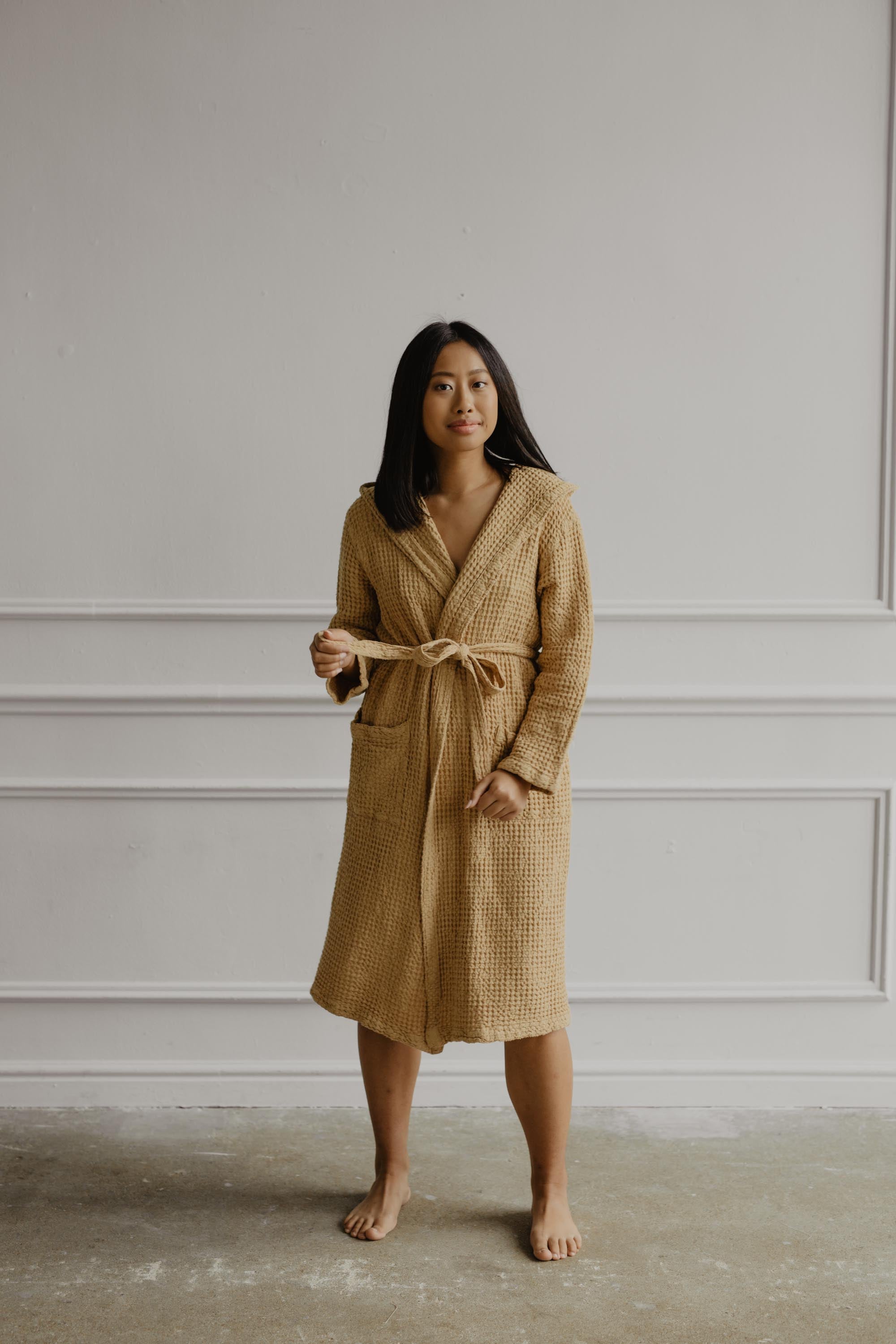 Woman Wearing A Mustard Color Linen Waffle Bathrobe In A White Room