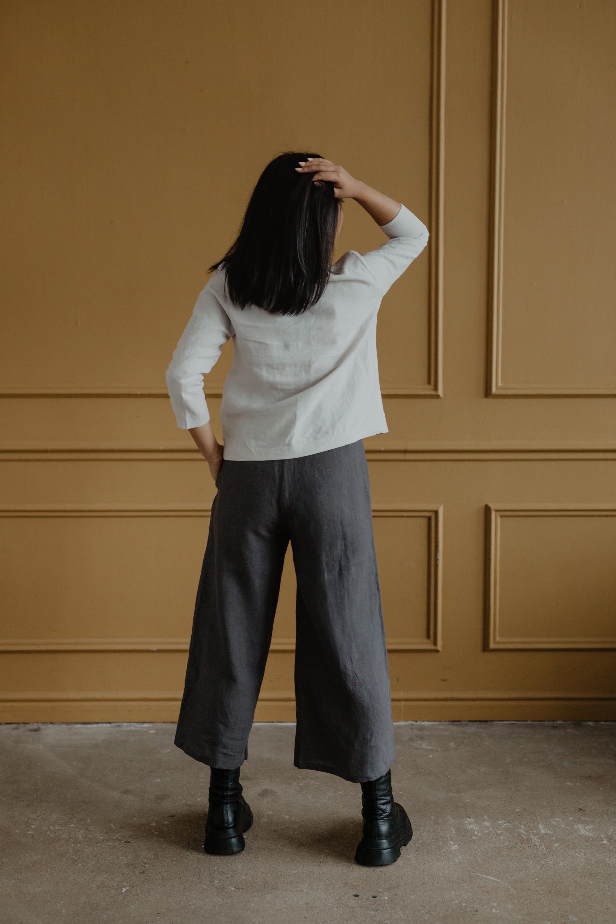 Woman Facing Back Wearing A White Linen Top and Grey Linen Pants By AmourLinen