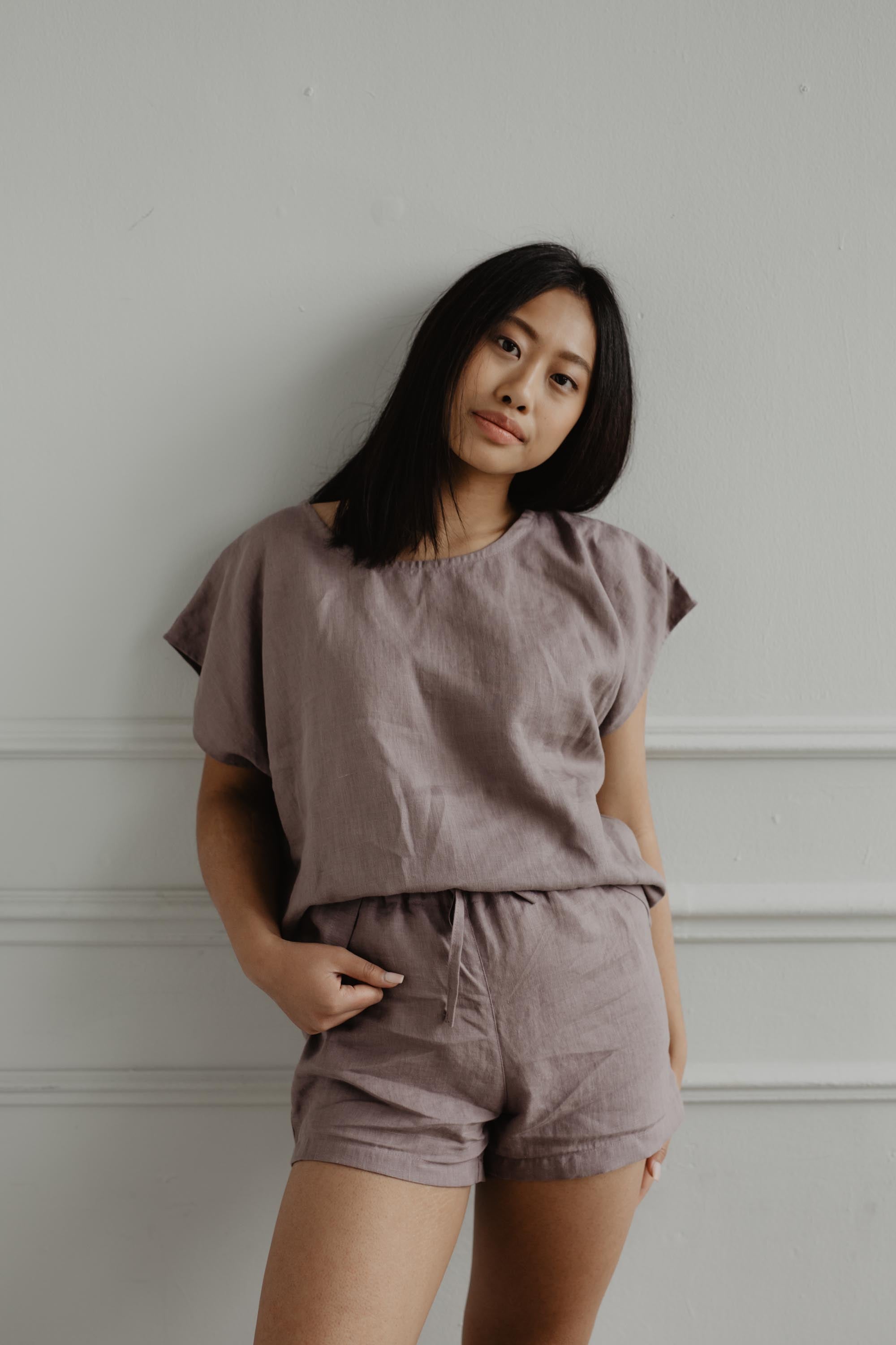 Woman Wearing Rosy Brown Linen Short Sleeve Pajama Leaning Against A Wall