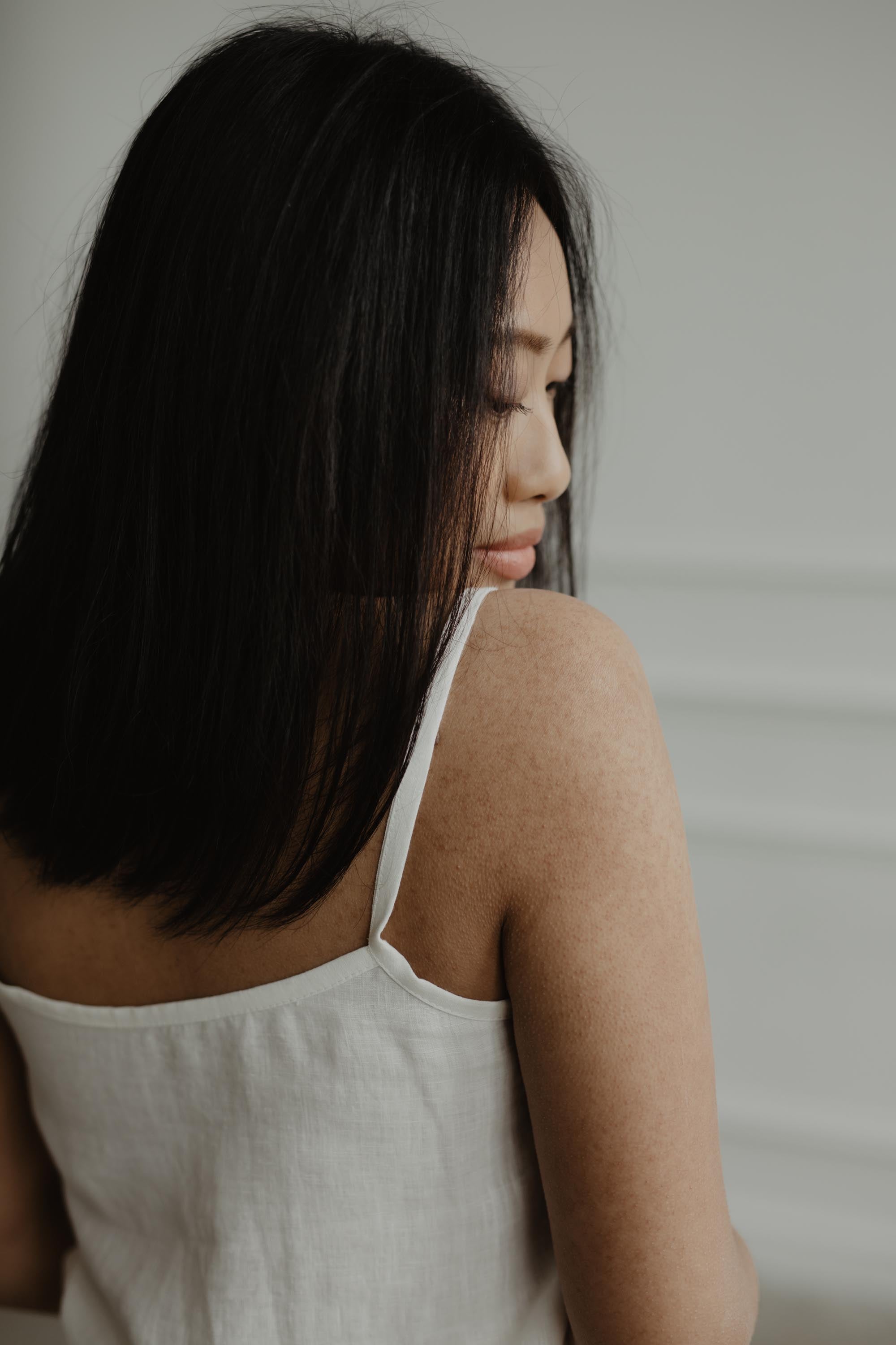 Close Up Of Womans Back Wearing A White Sleeveless Linen Pajama