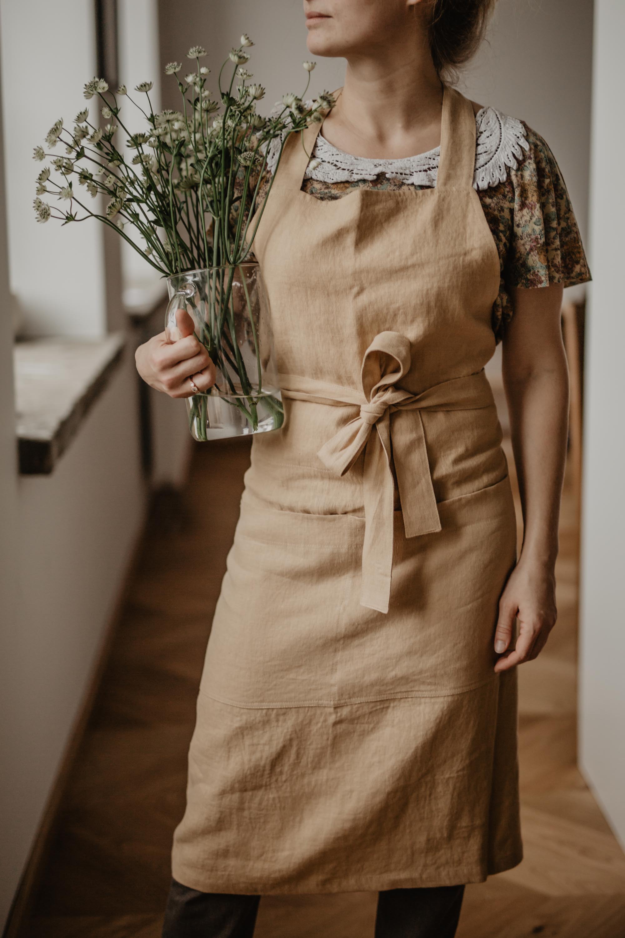 Woman Holding Flowers Wearing A Mustard Linen Bib Apron By AmourLinen