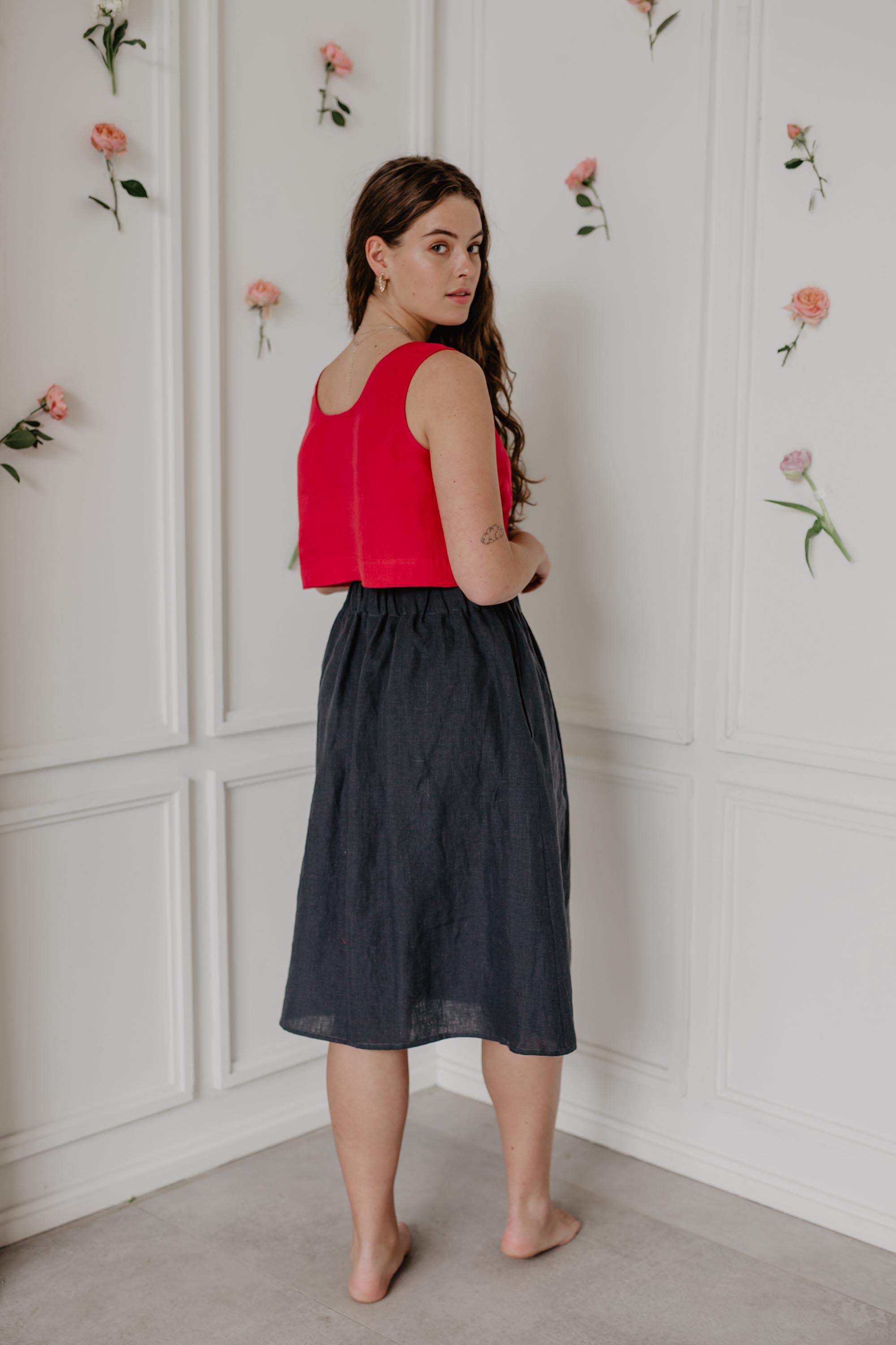 Woman Wearing A Red Linen Crop Top And Dark Linen Long Skirt Facing Back and Turning