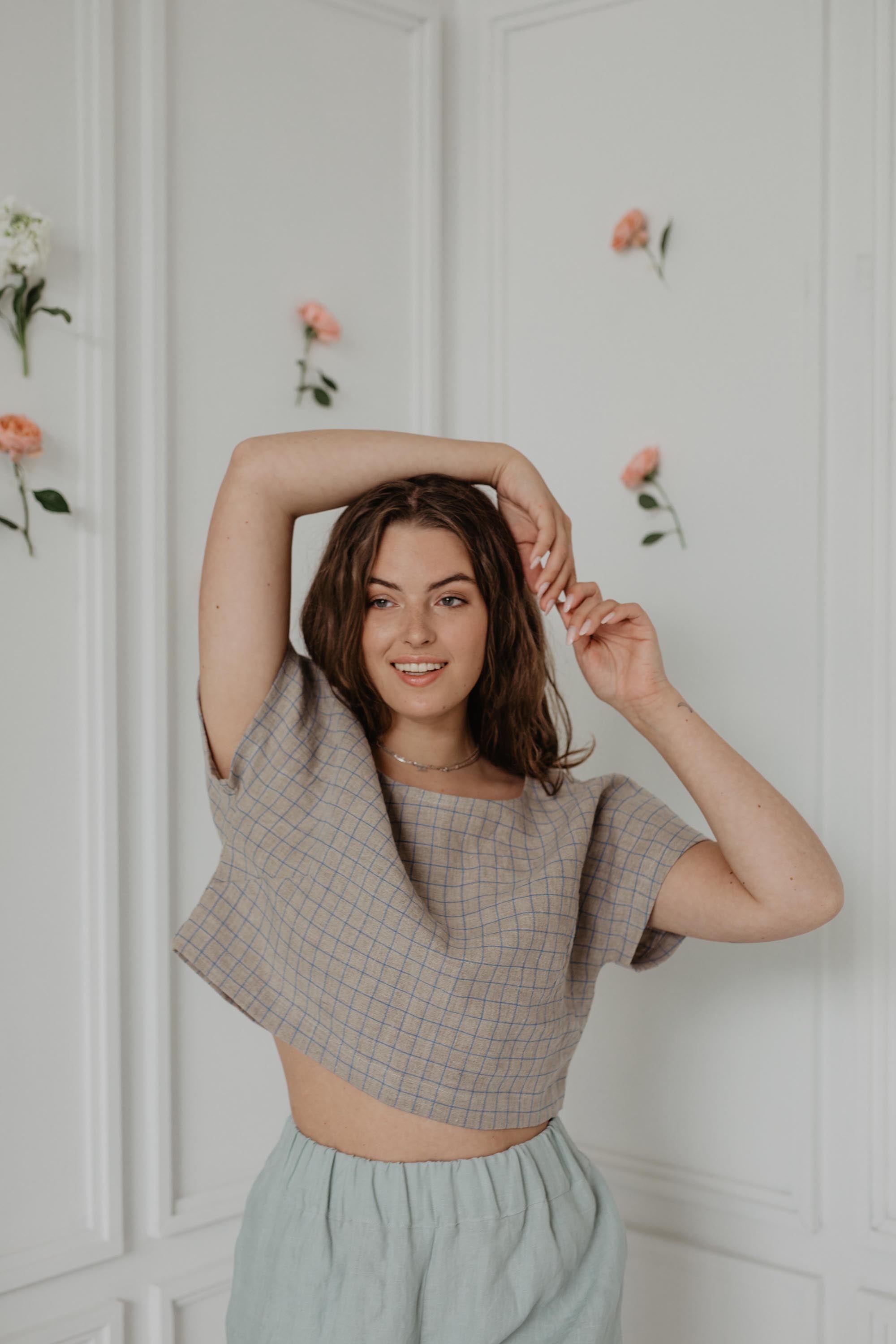 Woman Posing In White Room Wearing A Checkered Linen Crop Top WIth Buttons
