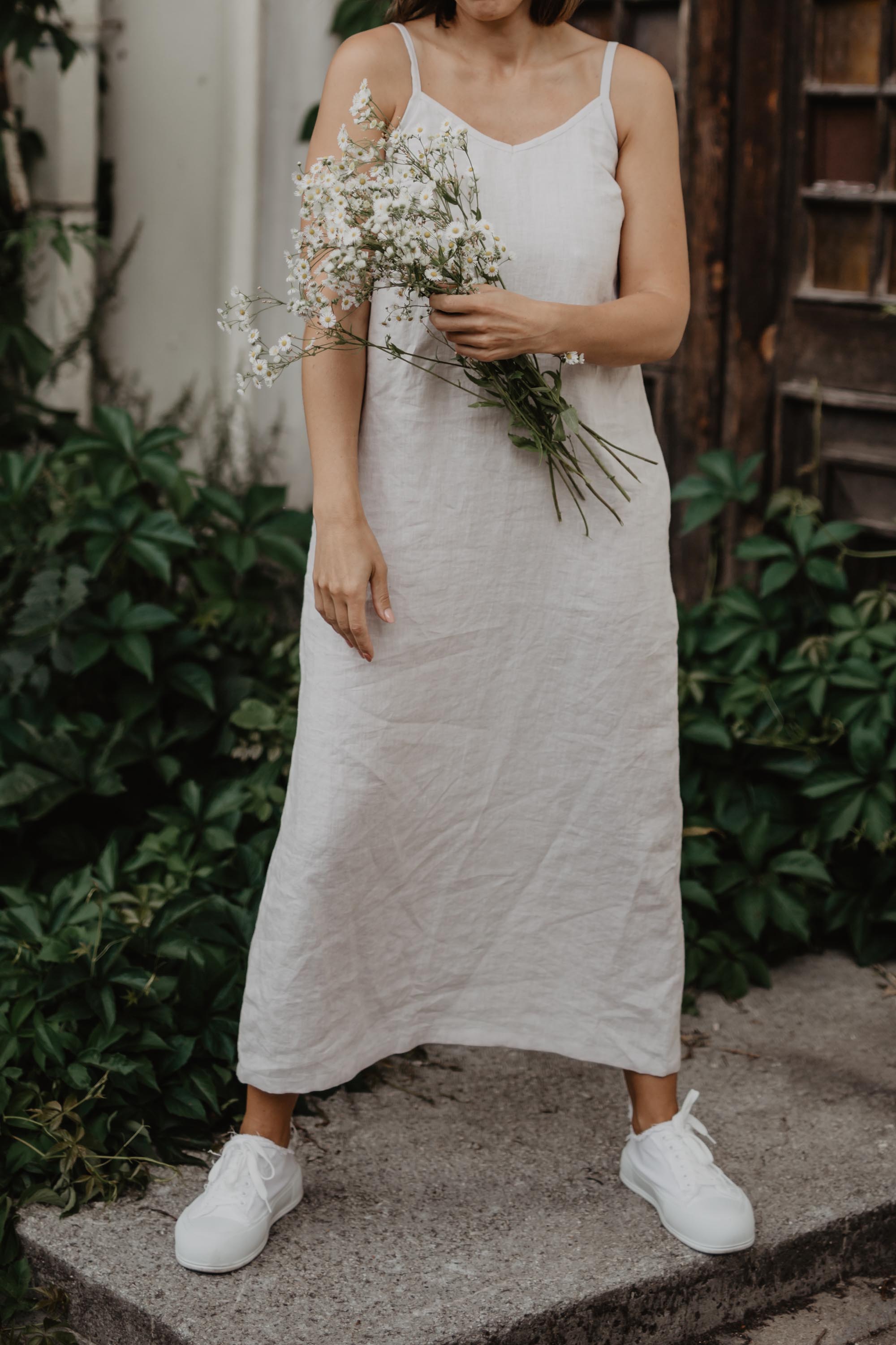 Wopman Holding Flowers Wearing A White Linen Dress