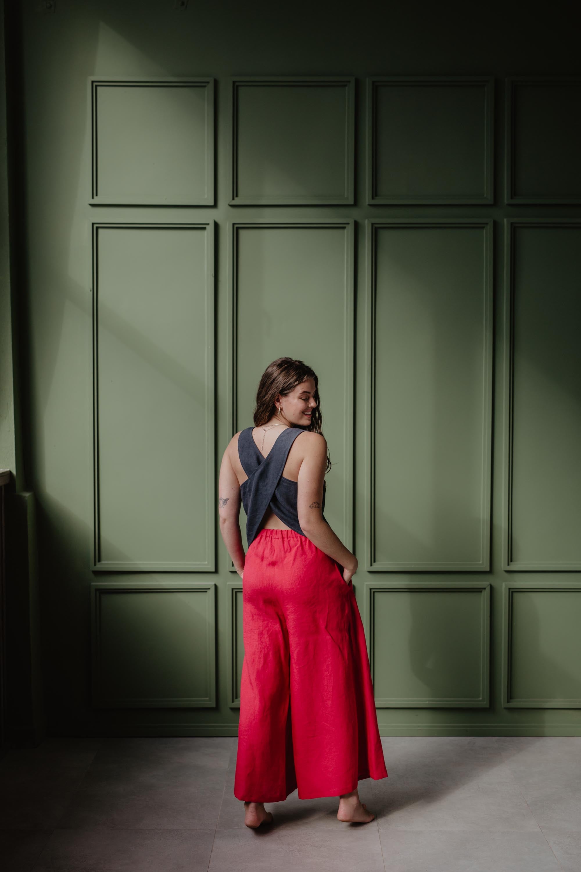 Back Of Woman Wearing Wide Magenta Linen Pants With Charcoal Top In A Green Room