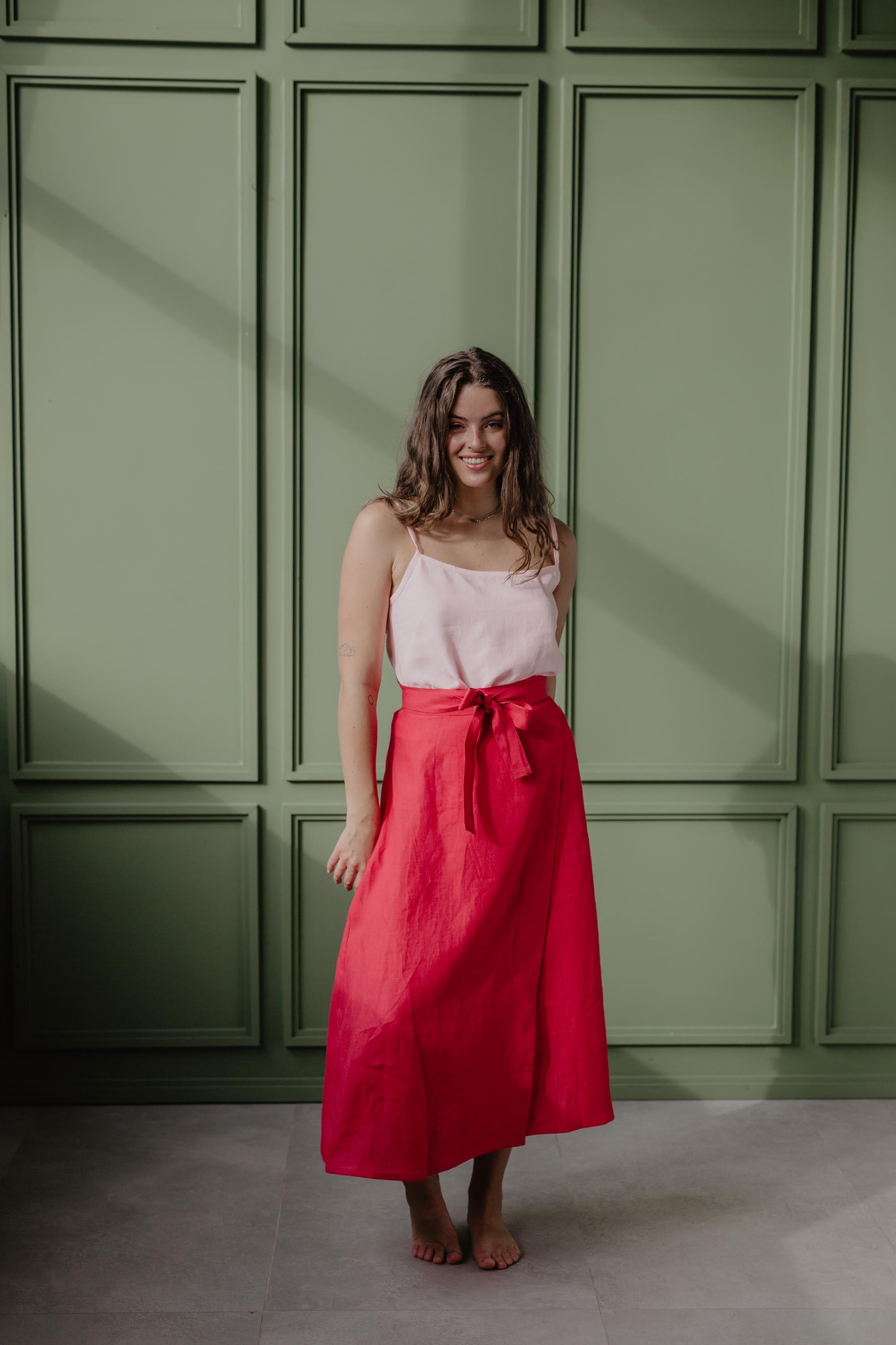 Fron View Of Woemn Wearing A Red Linen Wrap Skirt And Light Pink Top