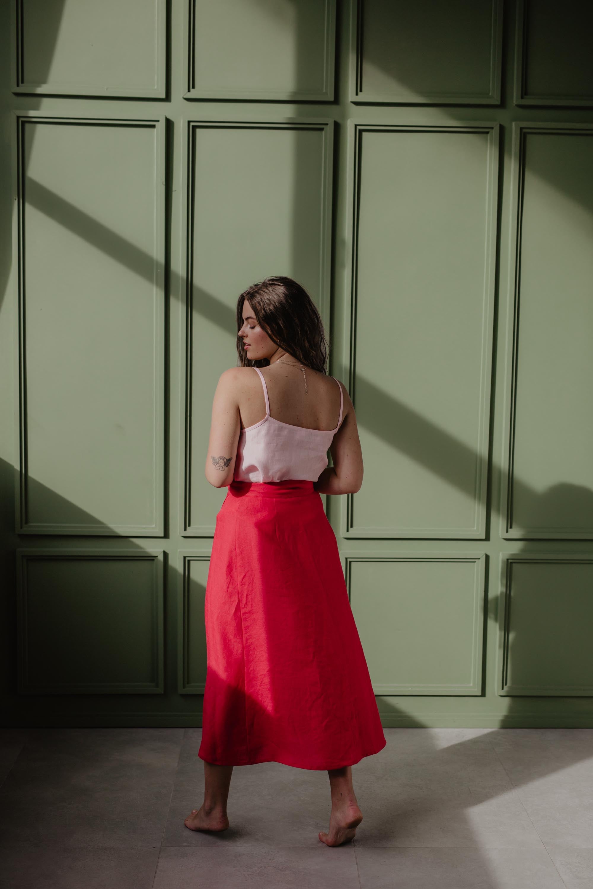 Back View Of Women Wearing A Red Linen Wrap Skirt And Light Pink Top