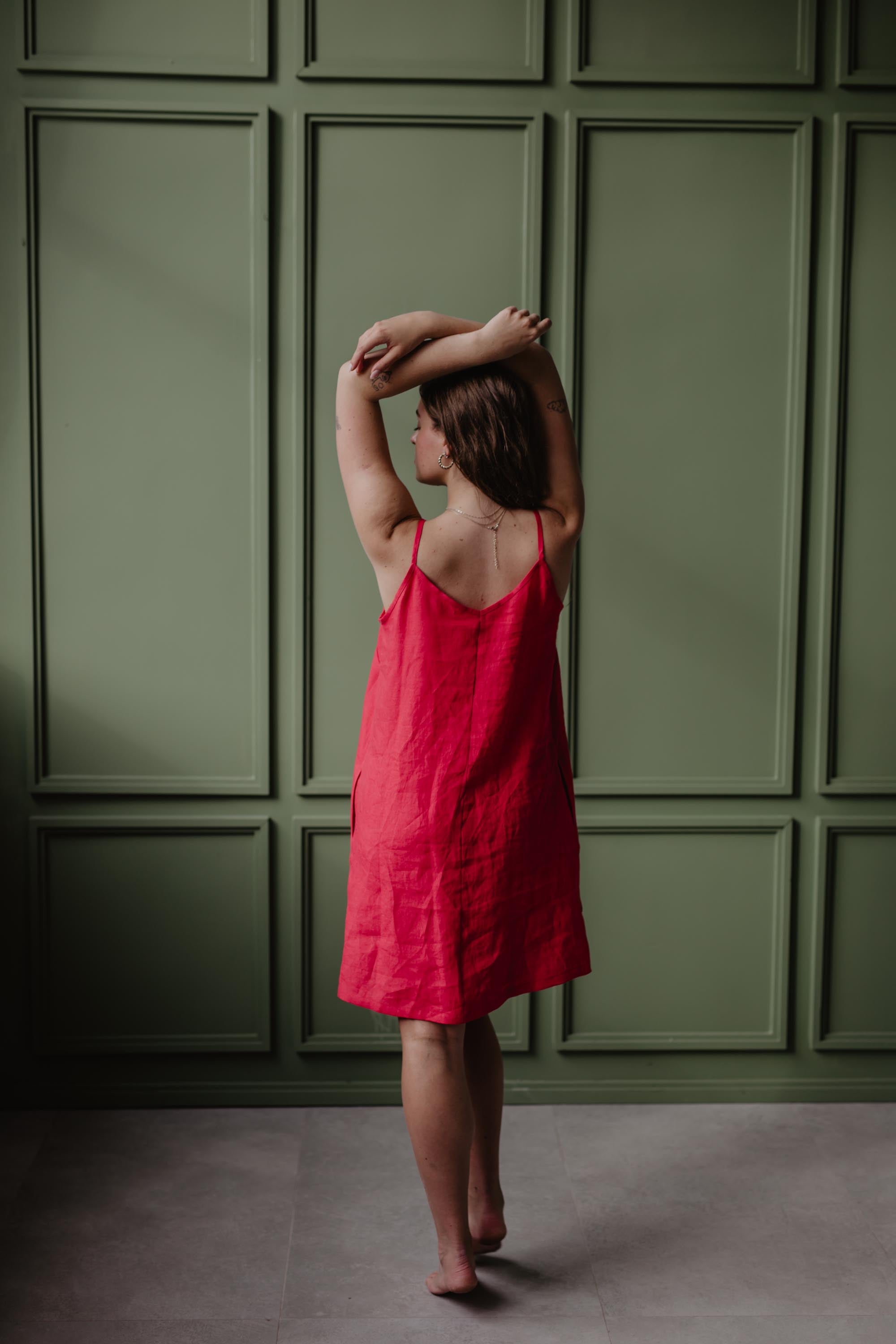 Back View Of Women Wearing A Red Linen Dress In A Dark Green Room by Amourlinen