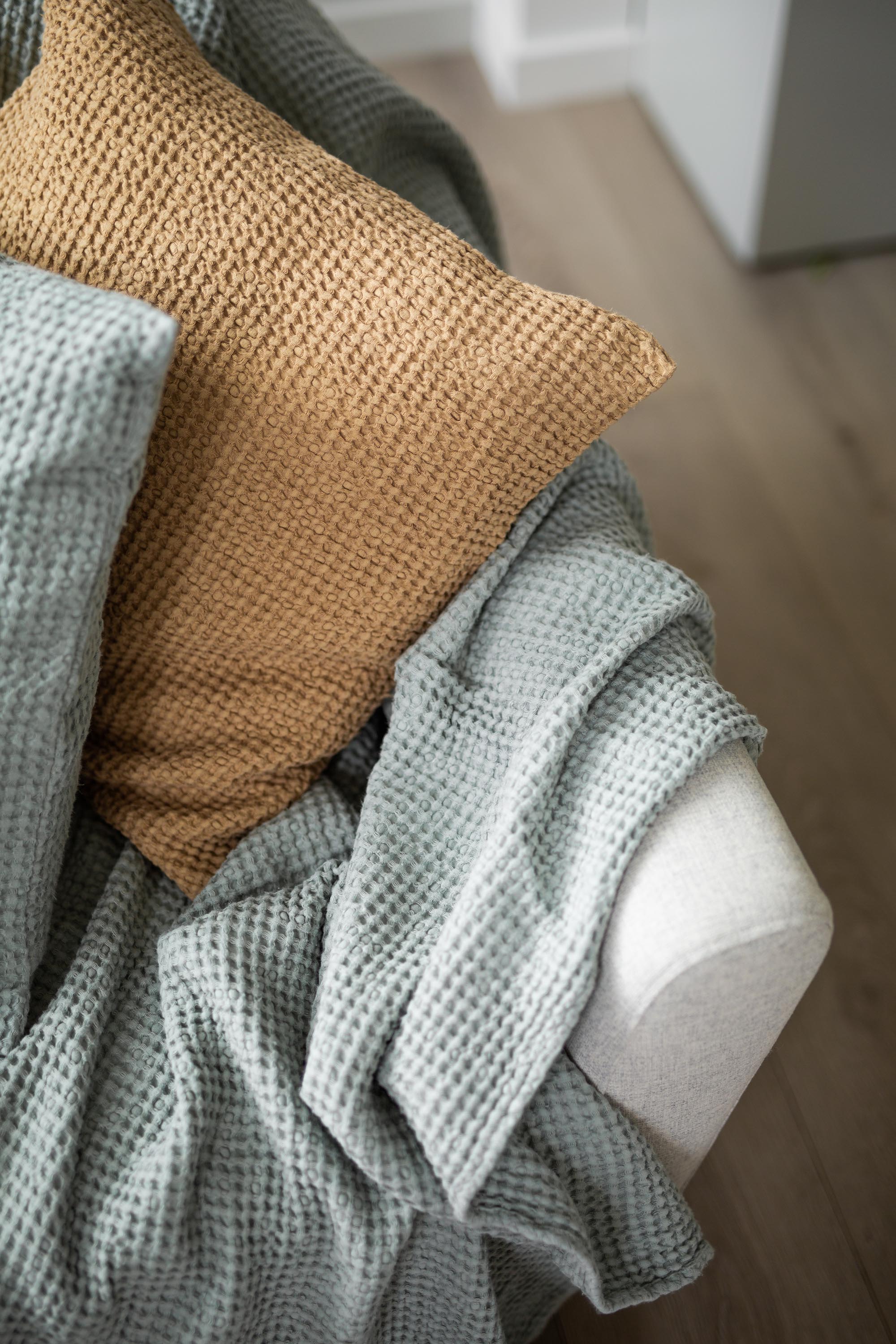 Close Up Of Sage Green Linen Waffle Blanket On Sofa With Pillows By AmourLinen